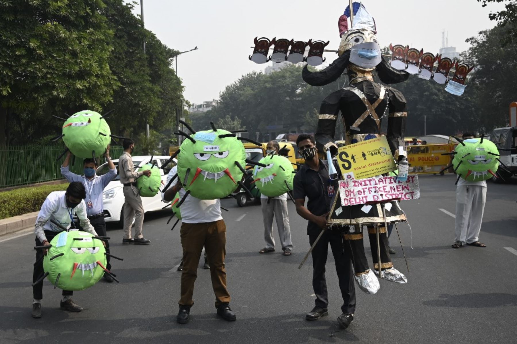 Oficiales de la oficina del magistrado de distrito sostienen mascotas con temática del coronavirus  y una efigie del demonio hindú Rey Ravana,  en una carretera durante una campaña de concientización contra el covid-19. Foto:AFP