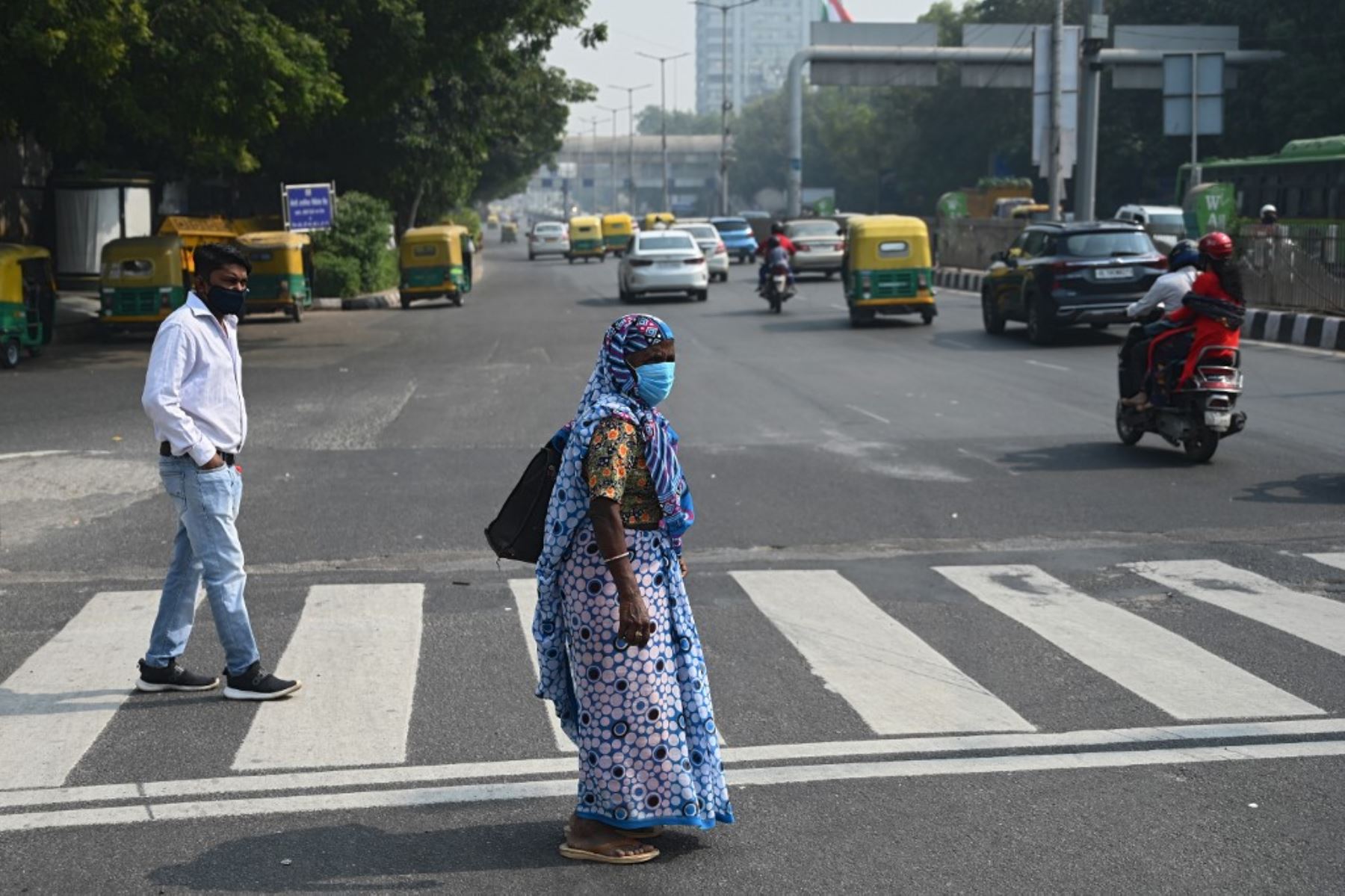 Los peatones que usan mascarillas como medida preventiva contra el covid-19 esperan para cruzar un concurrido cruce de carreteras en Nueva Delhi. Foto:AFP