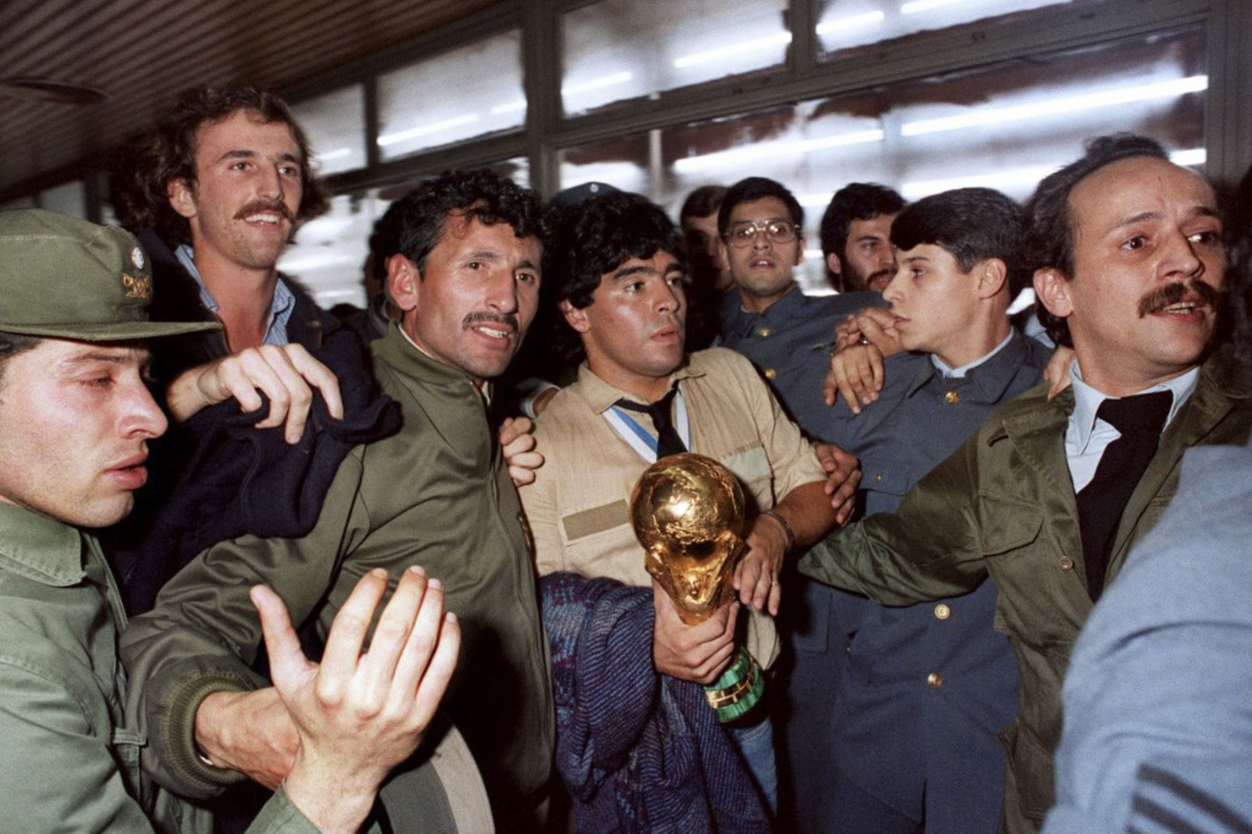 Diego Maradona, ganador de la Copa Mundial de la FIFA en 1986 en México, la copa en sus brazos, rodeado de simpatizantes y agentes de seguridad, llegó el 30 de junio de 1986 al aeropuerto de Buenos Aires procedente de México. Foto: AFP