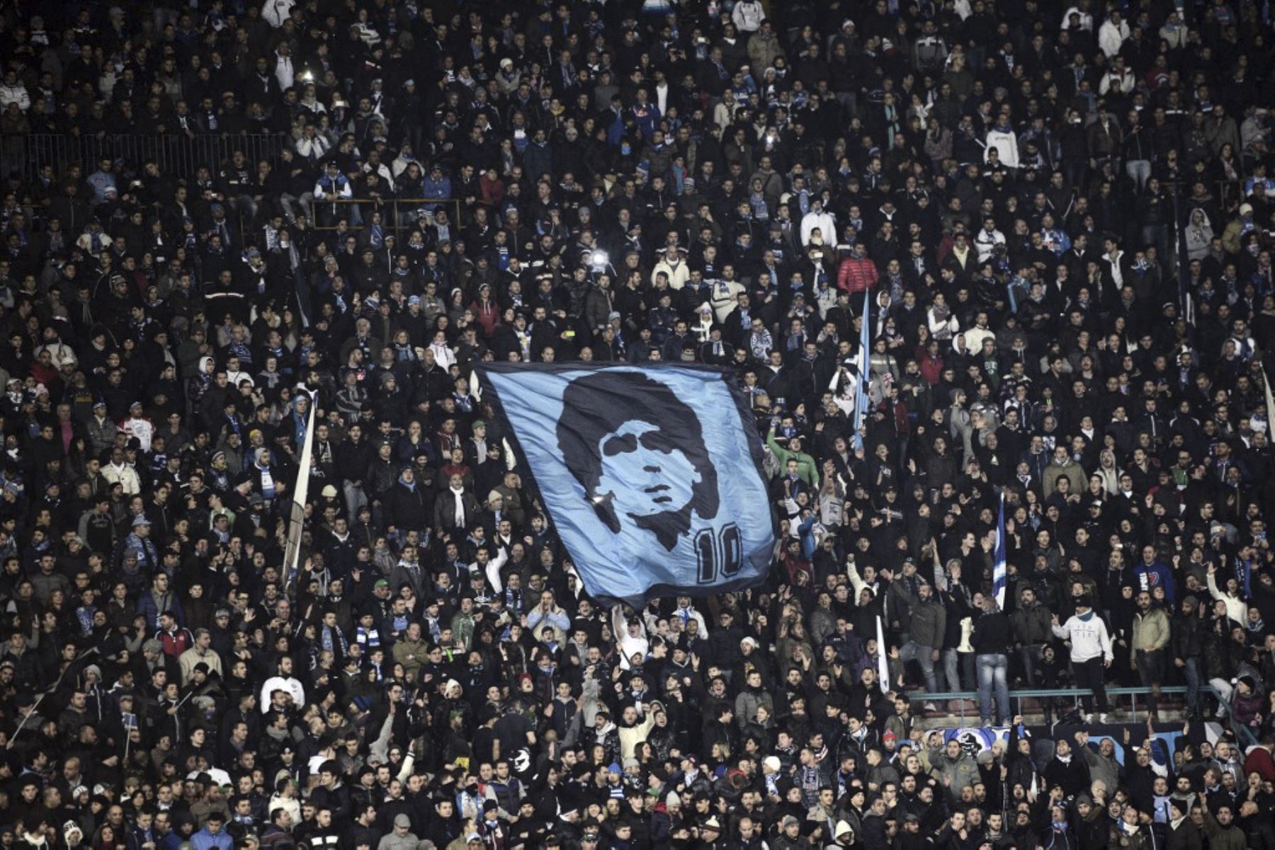 Los fanáticos del SSC Napoli muestran una bandera representando al ex jugador argentino del SSC Napoli Diego Armando Maradona durante el partido de fútbol de la Serie A SSC Napoli vs A.S. Roma en el estadio San Paolo de Nápoles el 6 de enero de 2013. Foto: AFP