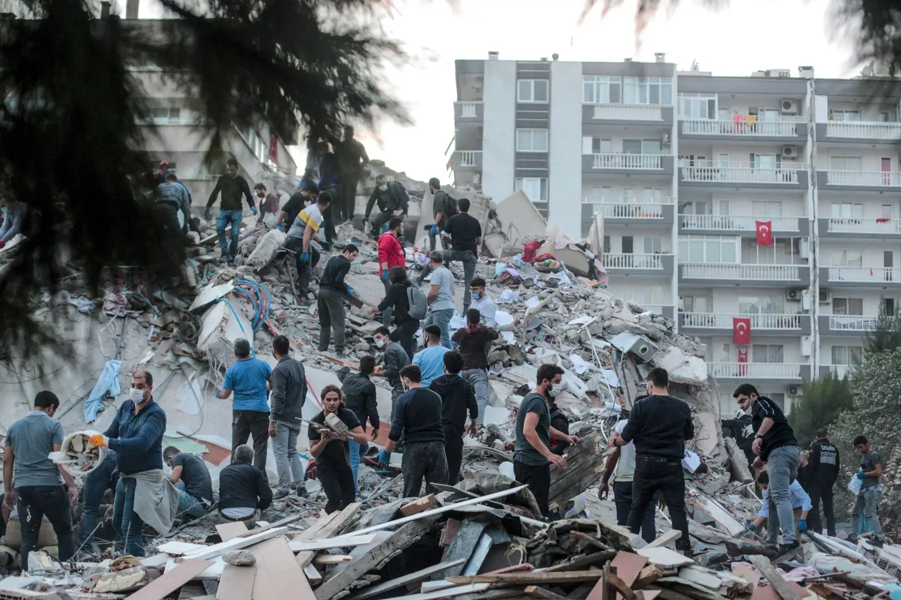 Los voluntarios limpian los escombros mientras buscan sobrevivientes en un edificio derrumbado después de que un fuerte terremoto sacudió la costa occidental del país y partes de Grecia, matando a cuatro personas e hiriendo a 120, en Izmir. Foto: AFP