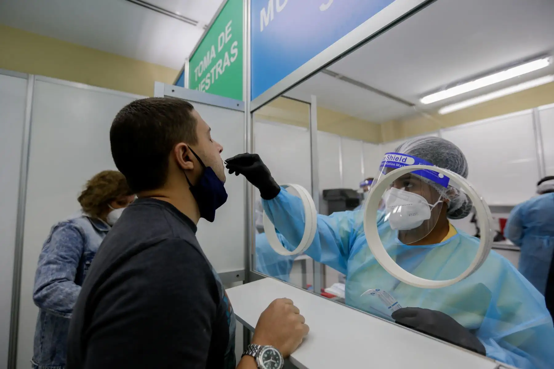 Un trabajador de la salud toma una muestra de hisopo de un hombre en una estación de pruebas rápidas de coronavirus en el Aeropuerto Internacional de Tocumen en la Ciudad de Panamá. Foto: AFP