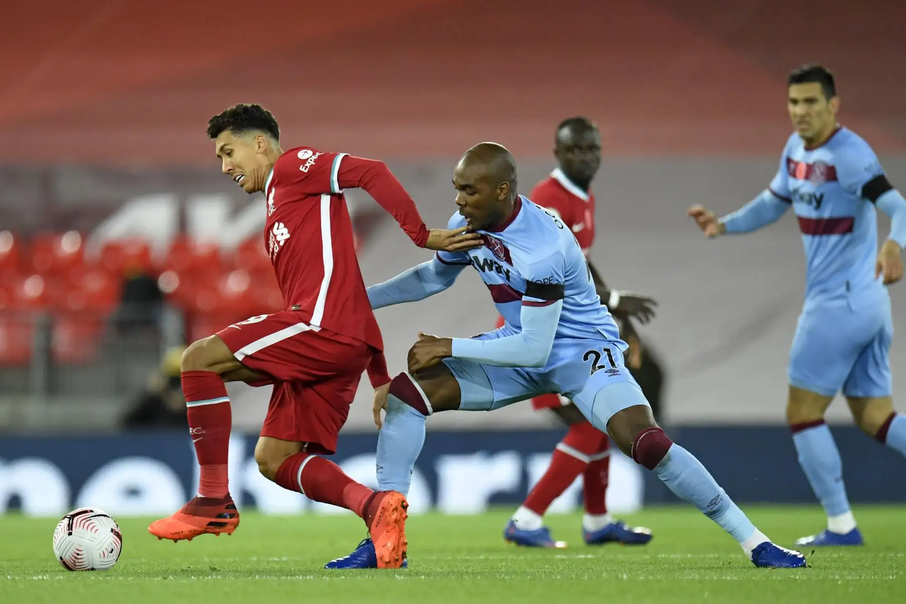 El mediocampista brasileño del Liverpool, Roberto Firmino, detiene al defensor italiano del West Ham United, Angelo Ogbonna, durante el partido de fútbol de la Premier League. Foto: AFP