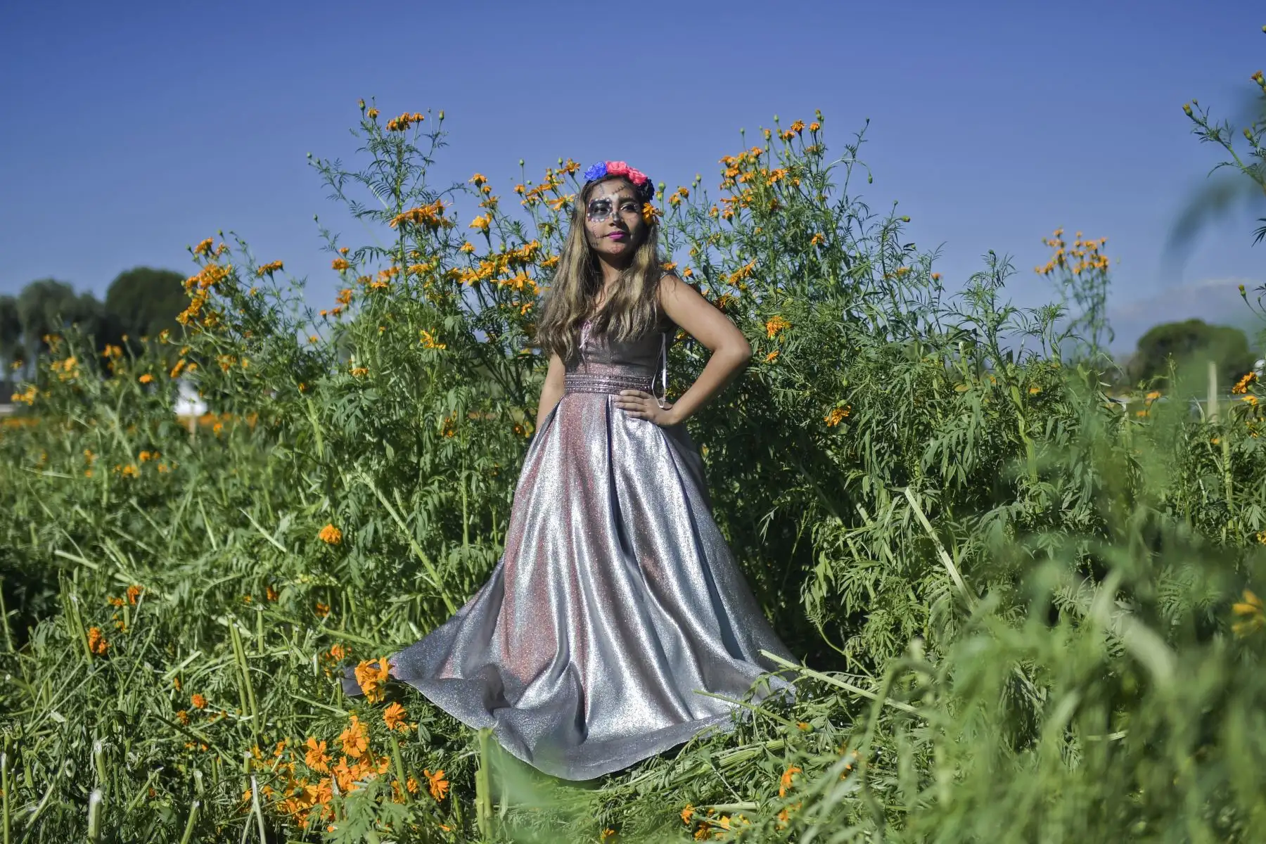 Una joven disfrazada  posa en un campo de cultivo en San Pedro Cholula, estado de Puebla, México, el 1 de noviembre de 2020, en el Día de Todos los Santos, en medio de la pandemia del coronavirus. Foto: AFP