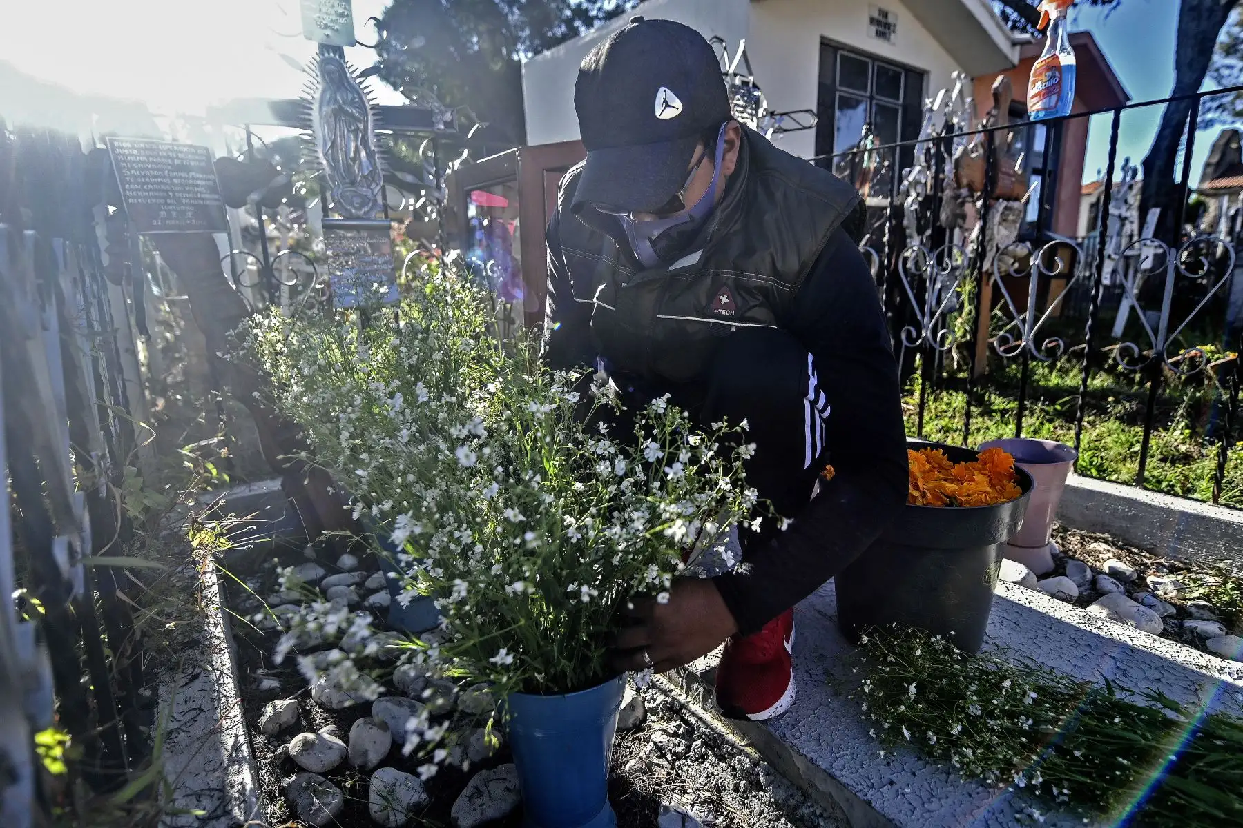 Un hombre decora la tumba de un familiar en el Panteón de La Magdalena, en San Pedro Cholula, estado de Puebla, México, el 1 de noviembre de 2020, el Día de Todos los Santos, en medio de la pandemia del coronavirus. Foto: AFP