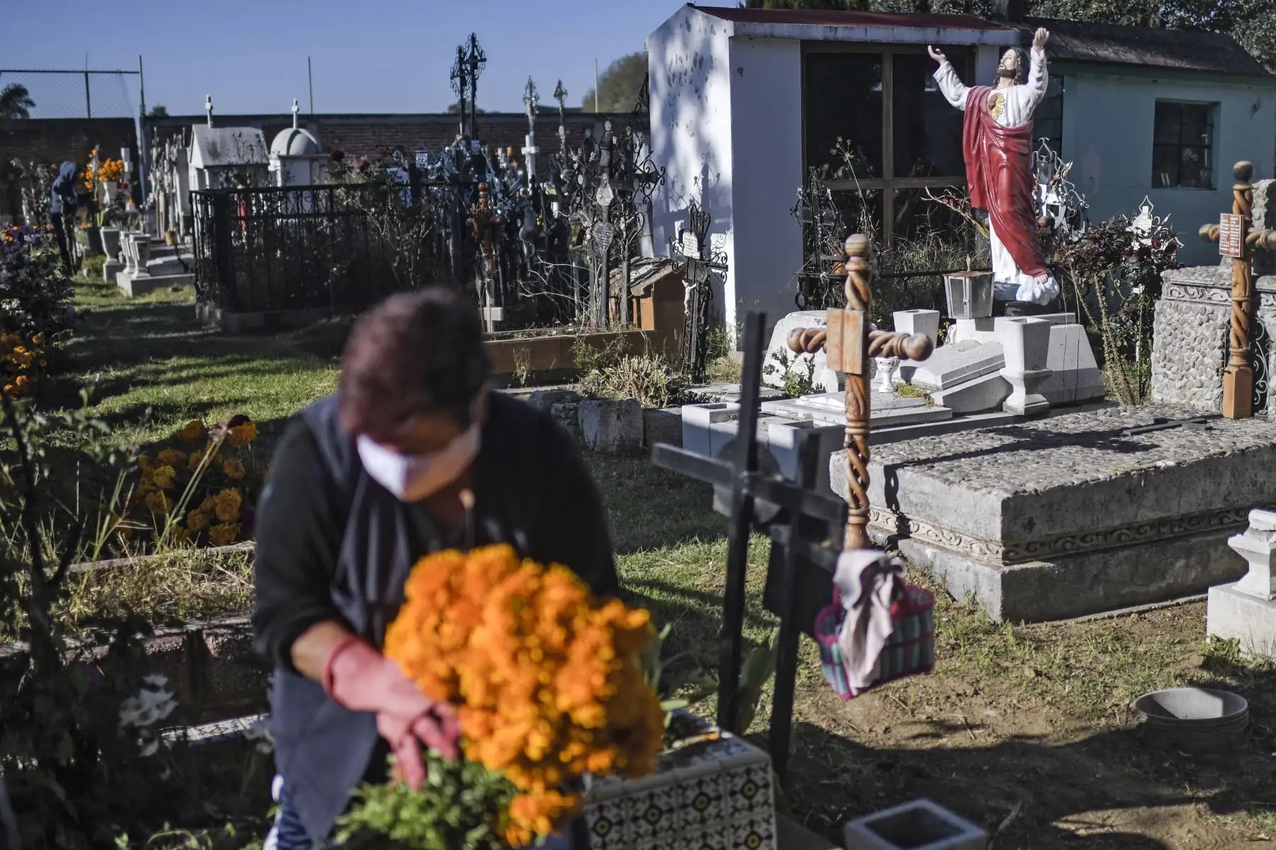 Una mujer decora la tumba de un familiar en el Panteón La Magdalena, en San Pedro Cholula, estado de Puebla, México, el 1 de noviembre de 2020, el Día de Todos los Santos, en medio de la pandemia del coronavirus. Foto: AFP