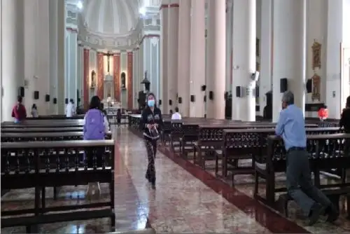 Personal del templo toma la temperatura a los fieles y estos deben pasar por la desinfección del calzado y aplicación de alcohol en las manos.
