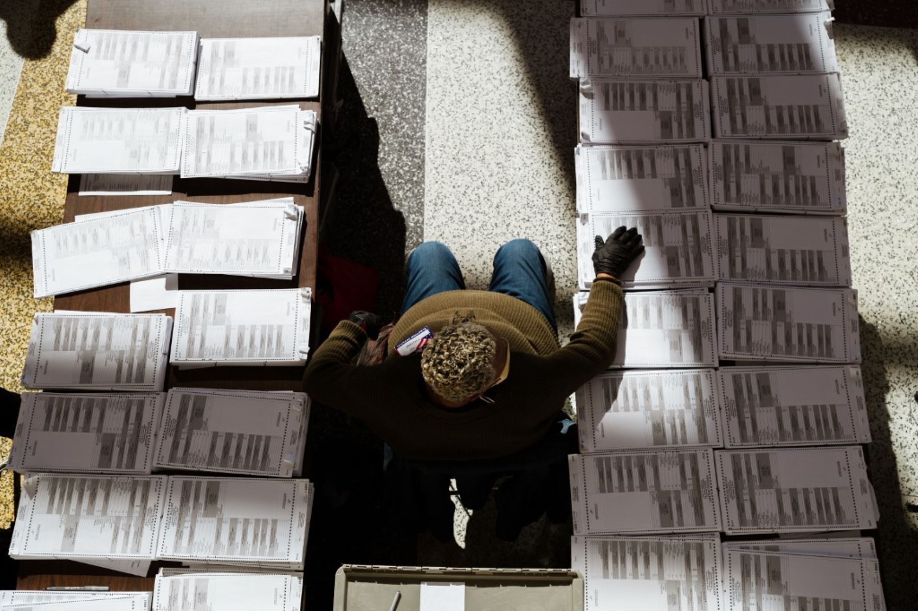 Un funcionario electoral se sienta entre pilas de boletas en blanco en el área de votación en el KFC YUM! Center el 3 de noviembre de 2020 en Louisville, Kentucky. Foto: AFP