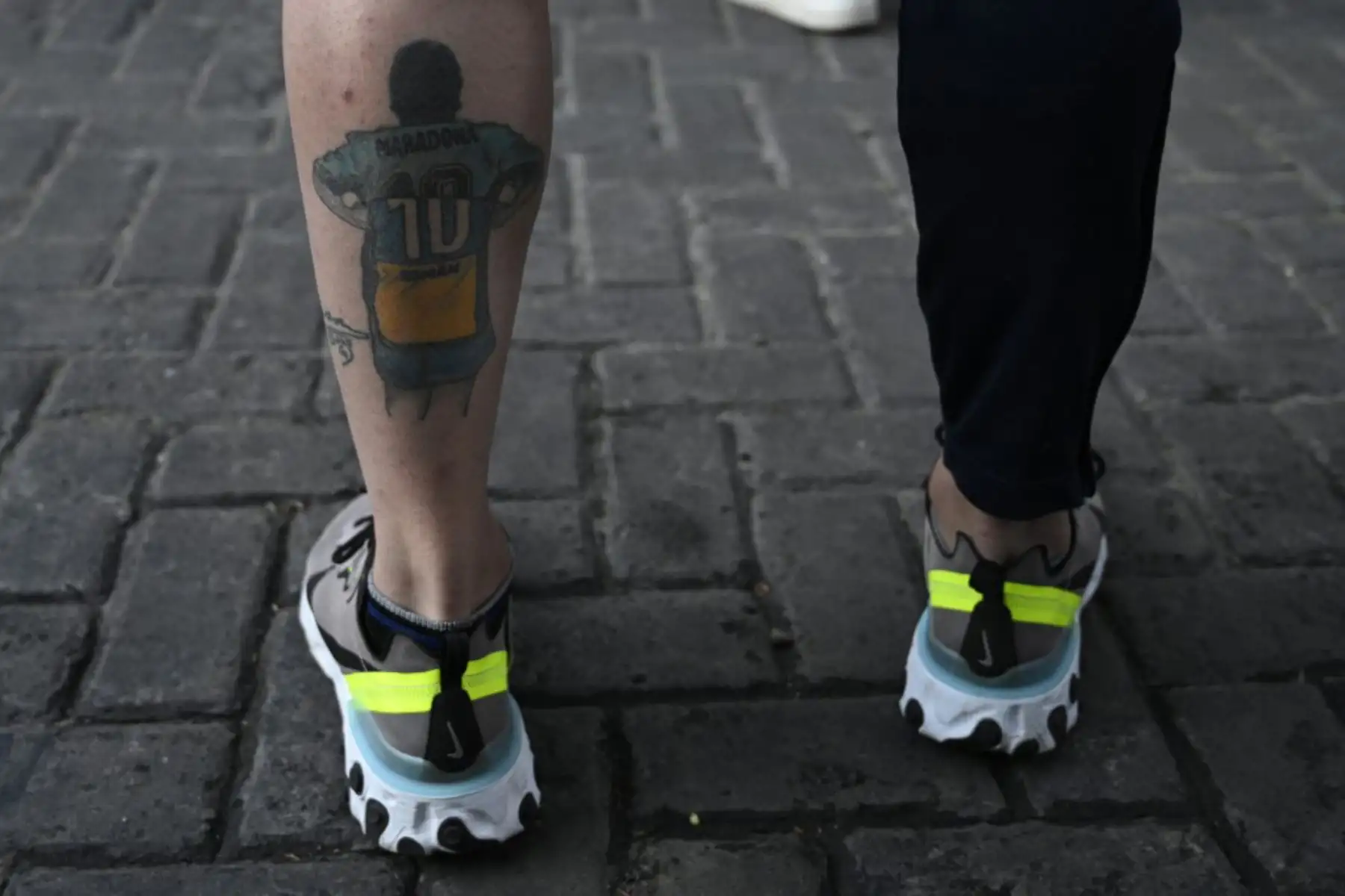 Un seguidor del exfutbolista argentino y entrenador de Gimnasia y Esgrima La Plata Diego Maradona muestra su tatuaje, afuera del hospital donde fue operado en Olivos, provincia de Buenos Aires

Foto:AFP