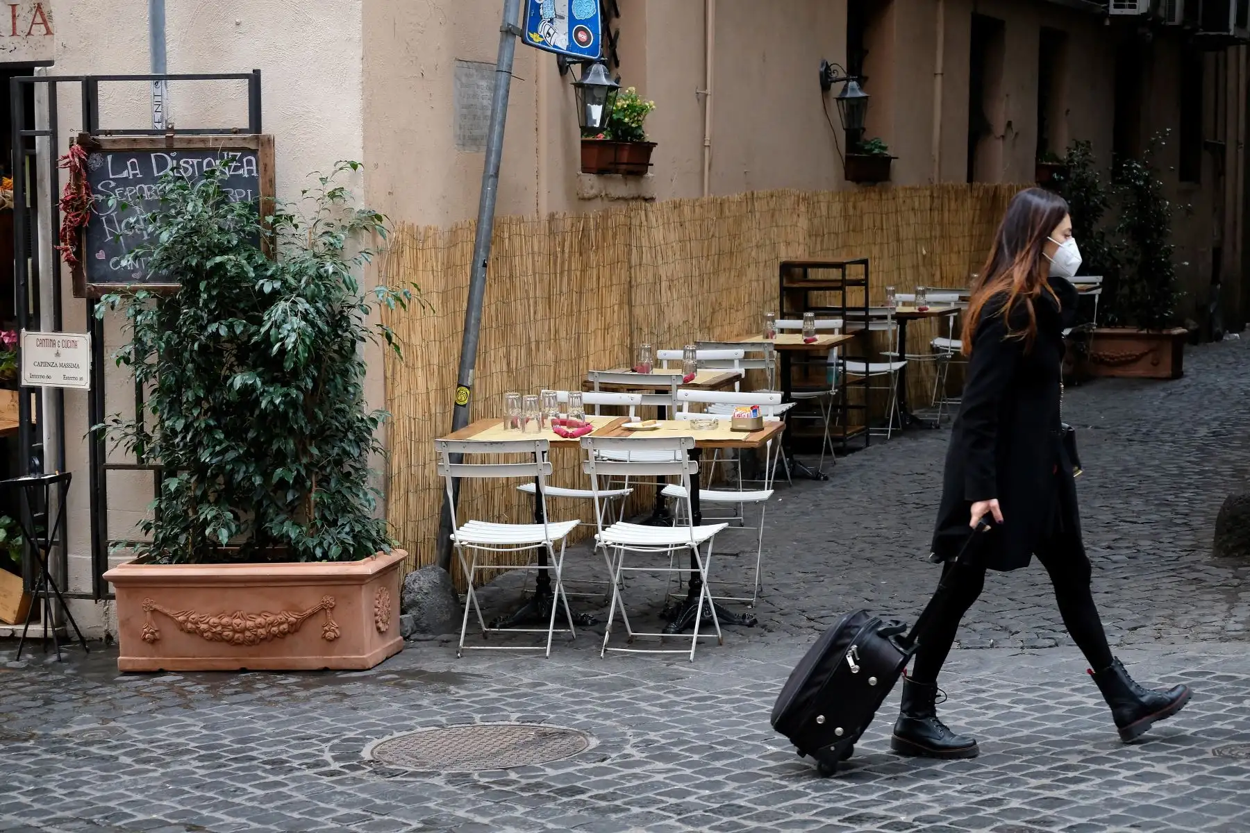 Una mujer con máscara protectora saca una maleta mientras pasa junto a las mesas de café vacías mientras el gobierno introduce nuevas medidas de restricción para frenar la propagación del nuevo coronavirus.
Foto: AFP