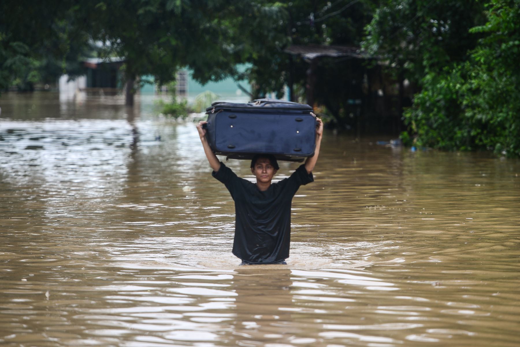 Una mujer vadea cargando un equipaje por una calle inundada luego del desborde del río Ulúa en el municipio de El Progreso, departamento de Yoro, Honduras  debido a las fuertes lluvias provocadas por el huracán Eta.
Foto: AFP