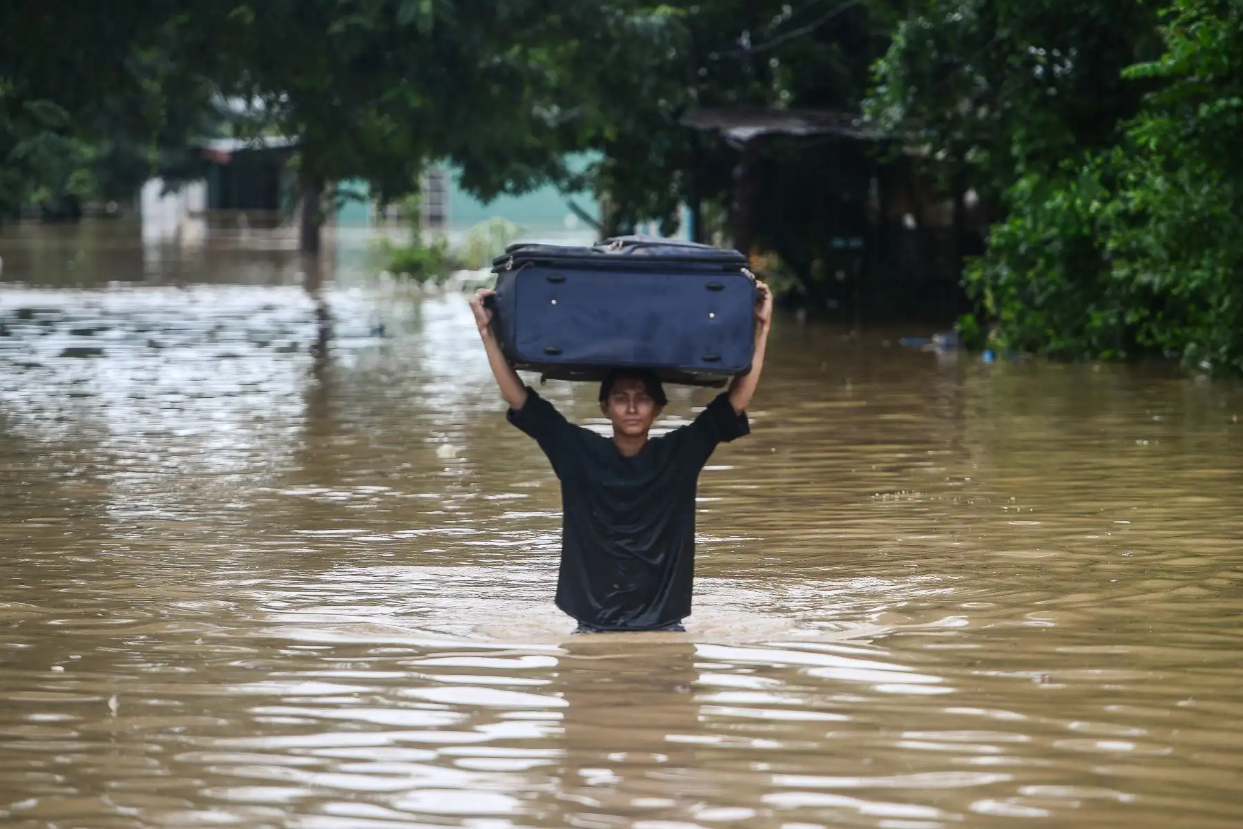 Una mujer vadea cargando un equipaje por una calle inundada luego del desborde del río Ulúa en el municipio de El Progreso, departamento de Yoro, Honduras  debido a las fuertes lluvias provocadas por el huracán Eta.
Foto: AFP