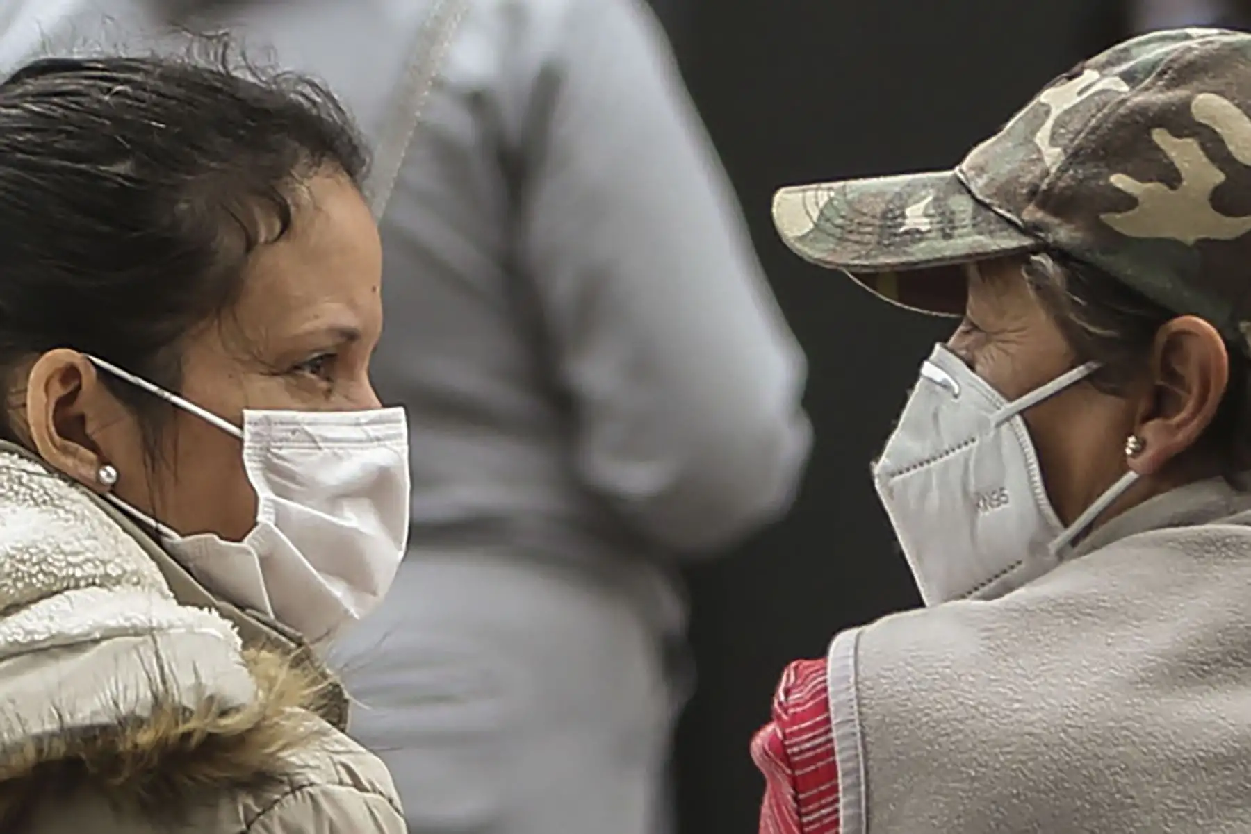 Mujeres con mascarilla hablan afuera de una carpa donde se atiende a pacientes con síntomas de covid-19, afuera del hospital IESS Sur, en Quito, el 20 de julio del 2020. Foto: AFP.