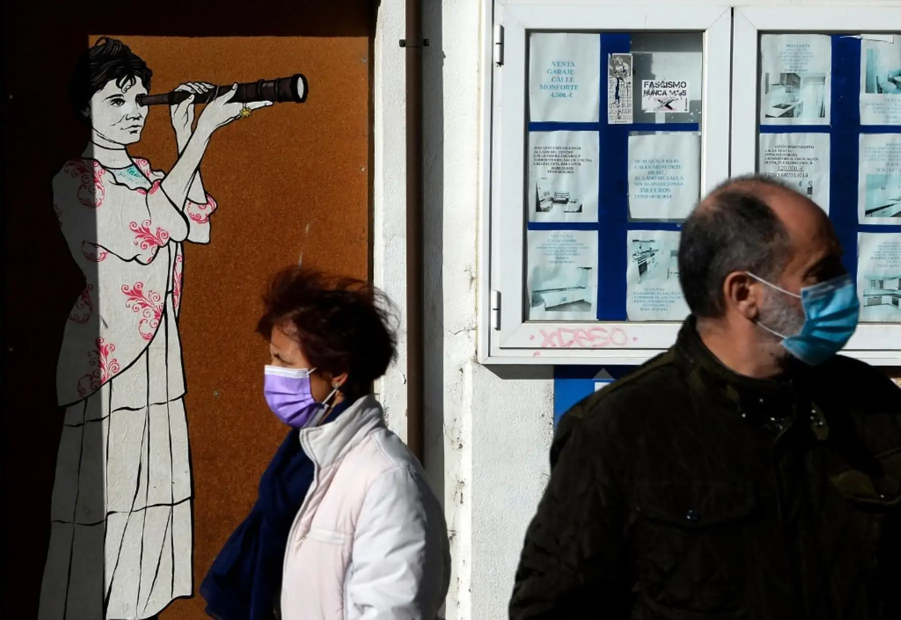 Dos personas con mascarillas pasan junto a un mural que representa a la poetisa gallega más destacada Rosalía de Castro, en Lugo. Foto: AFP