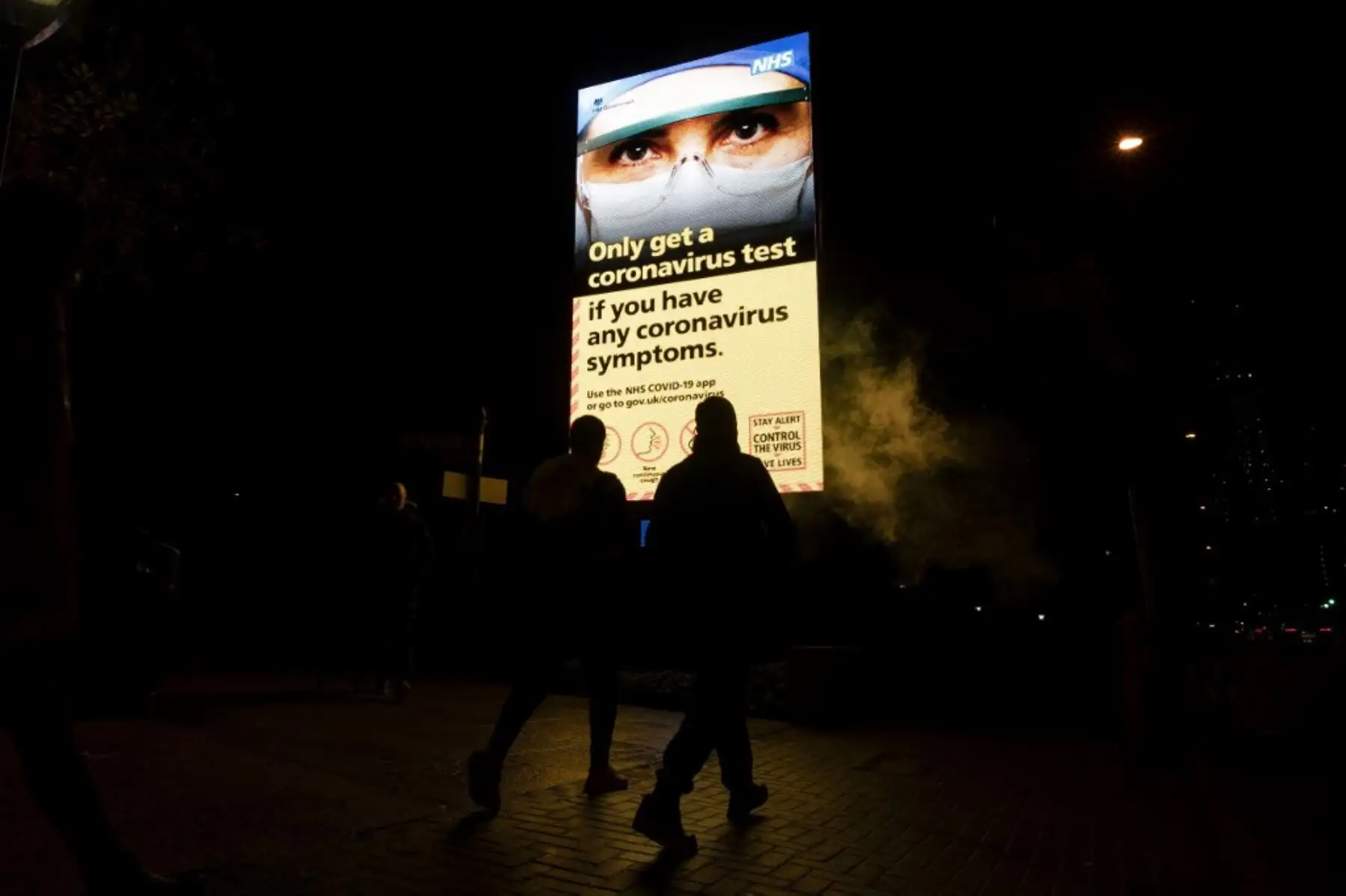 Los peatones pasan junto a una valla publicitaria que muestra un anuncio del gobierno que aconseja a las personas que se hagan la prueba de Covid-19 en el sur de Londres. Foto: AFP