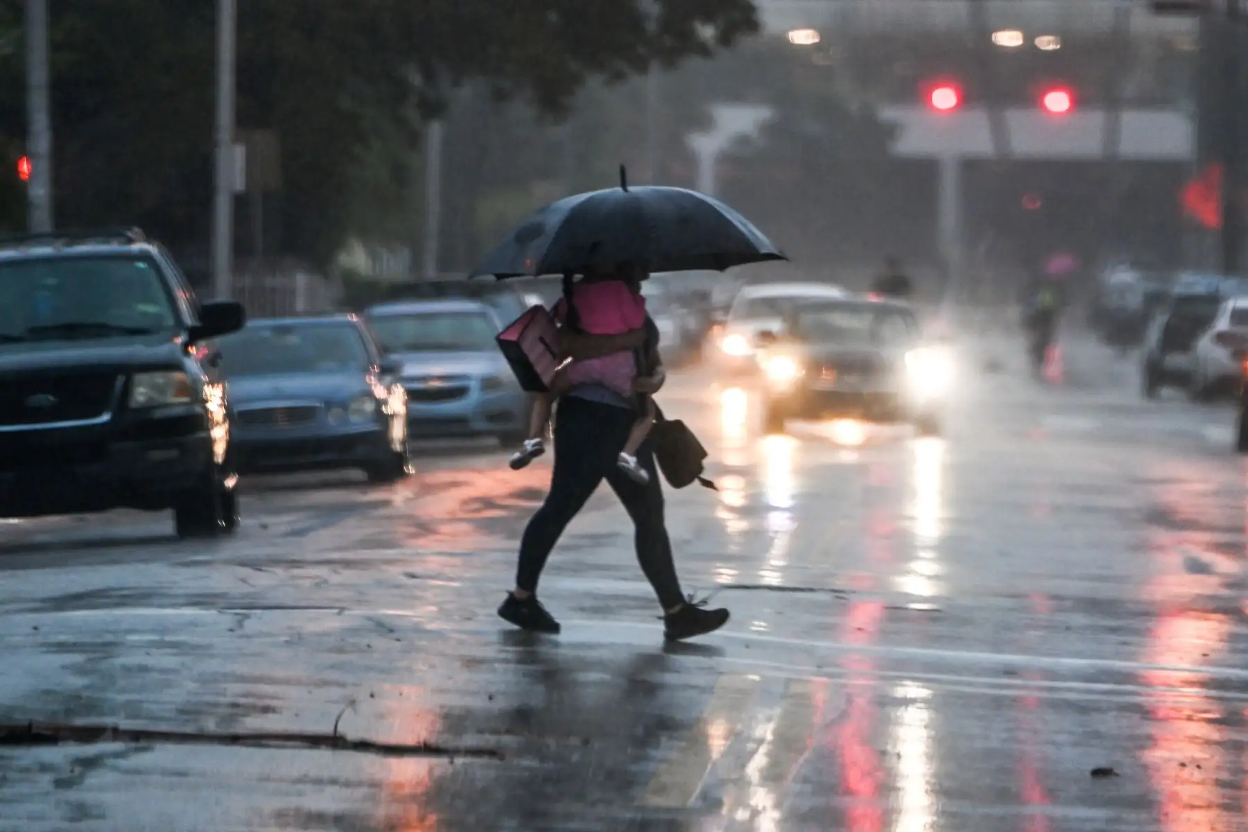Un hombre sostiene a su hija mientras cruza la carretera durante una fuerte lluvia y viento mientras la tormenta tropical Eta se acerca al sur de Florida, en Miami, Florida.
Foto: AFP