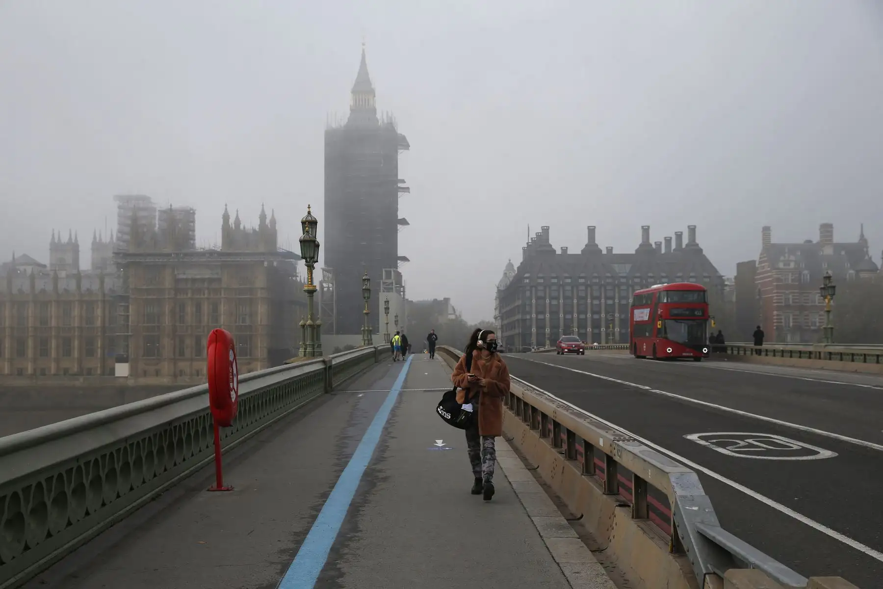 Una mujer con una máscara facial camina sobre el puente de Westminster, en el centro de Londres, cuando Inglaterra entra en un segundo bloqueo por coronavirus. Foto: AFP