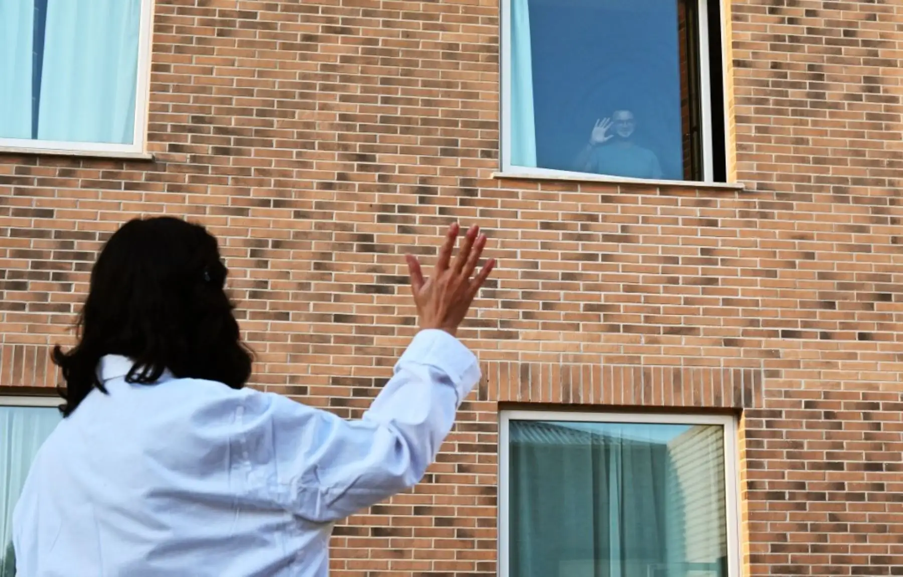 El paciente Christian Poretta, una enfermera de 23 años, saluda al personal médico desde la ventana de su habitación en el hotel Sheraton Parco de Medici de Roma. Foto: AFP