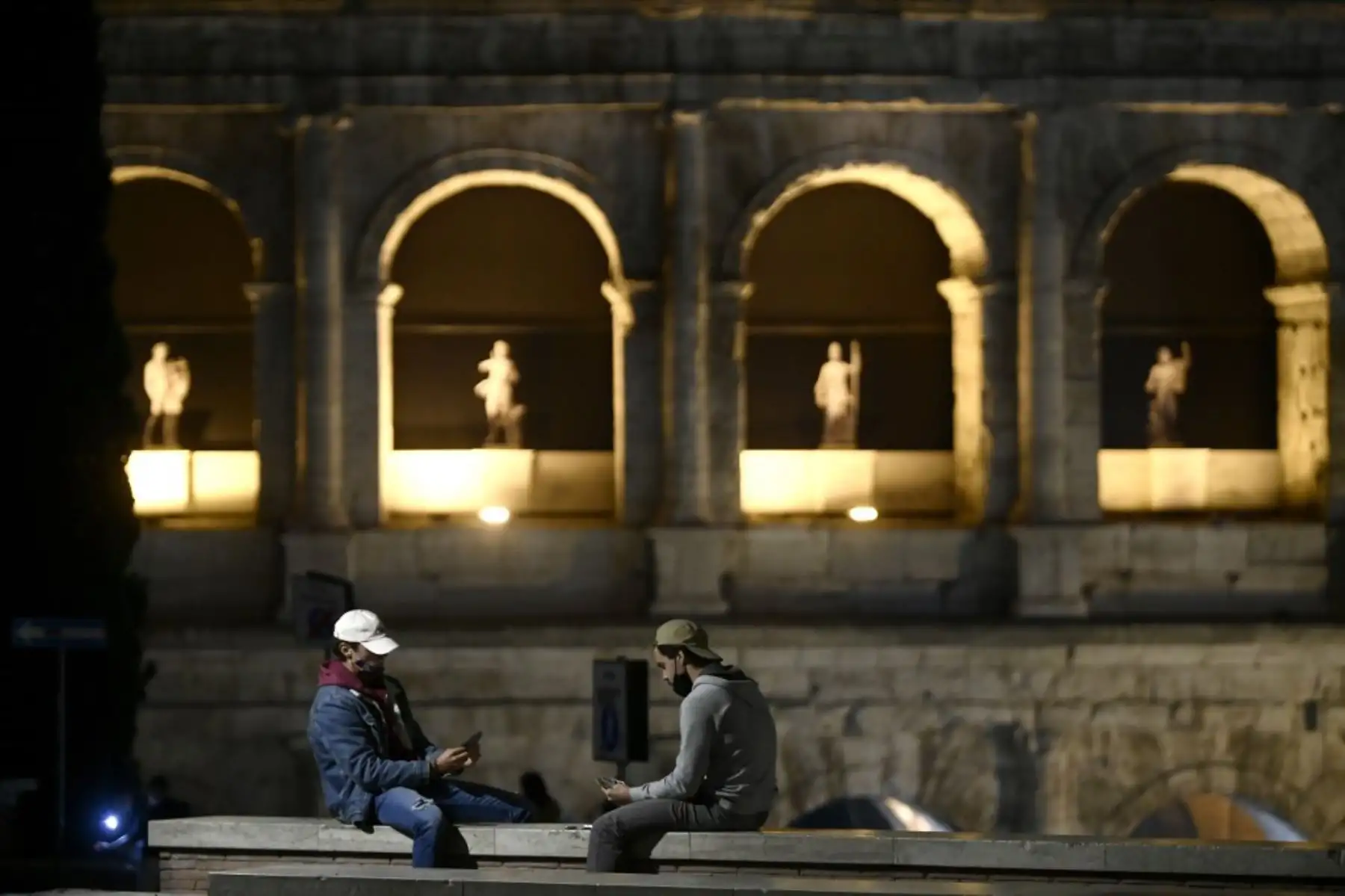 Las personas que usan máscaras protectoras juegan a las cartas en el Coliseo de Roma el 11 de noviembre de 2020, durante las medidas de restricción del gobierno para frenar la propagación de la pandemia Covid-19 causada por el nuevo coronavirus. Foto: AFP