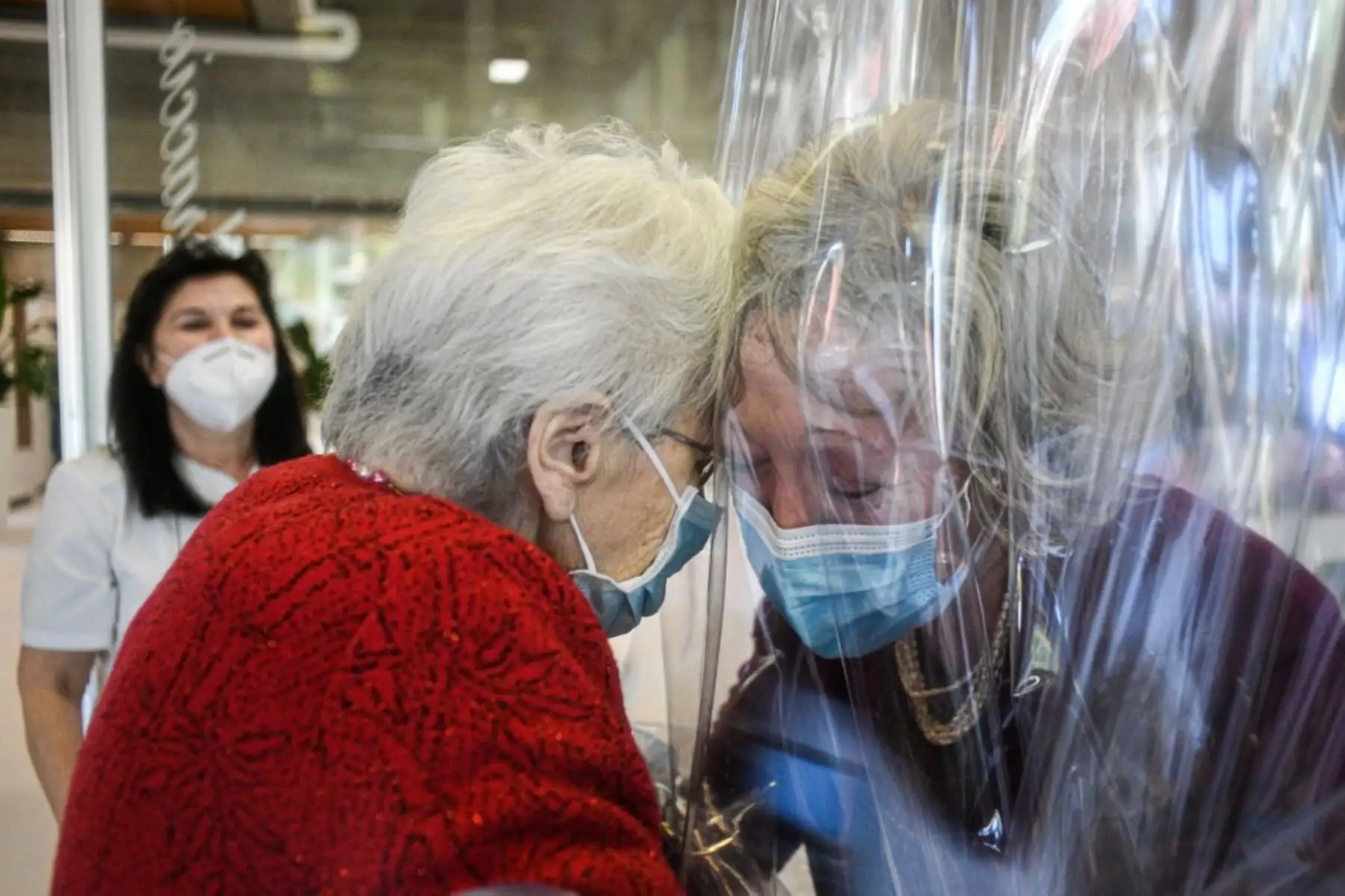 Una residente del asilo de ancianos Domenico Sartor en Castelfranco Veneto, cerca de Venecia, abraza a su hija visitante a través de una pantalla de plástico en una habitación llamada "Sala de Abrazo" en medio de la nueva pandemia de coronavirus. Foto: AFP