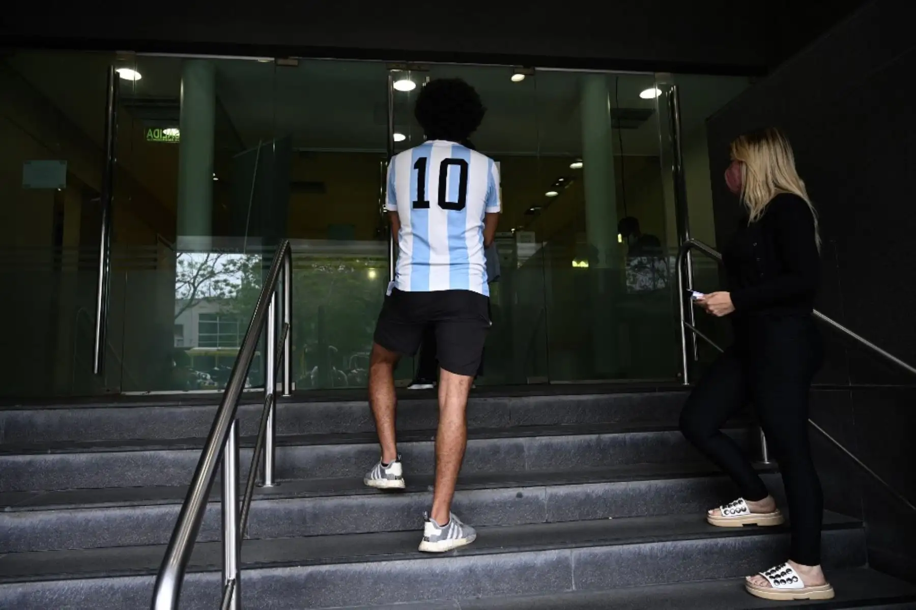 Un joven con camiseta de fútbol argentino aguarda en la entrada de la clínica privada donde el ex futbolista argentino y entrenador de Gimnasia y Esgrima La Plata Diego Maradona fue sometido a una cirugía cerebral por un coágulo de sangre, en Olivos, Provincia de Buenos Aires. Foto: AFP