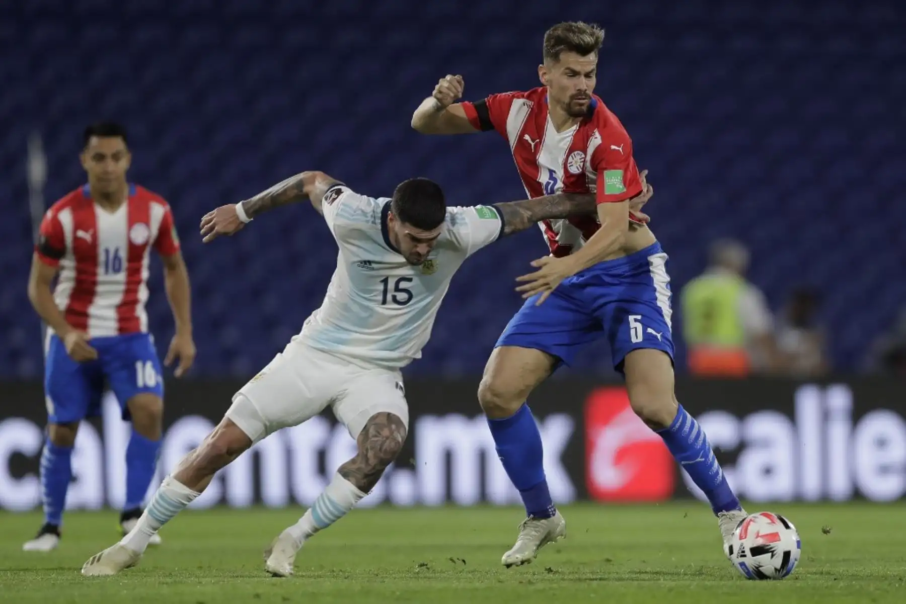 El argentino Rodrigo De Paul (izq.) Y el paraguayo Gastón Giménez compiten por el balón durante su partido de fútbol a puerta cerrada clasificatorio sudamericano para la Copa Mundial de la FIFA 2022 en el Estadio La Bombonera en Buenos Aires. Foto: AFP