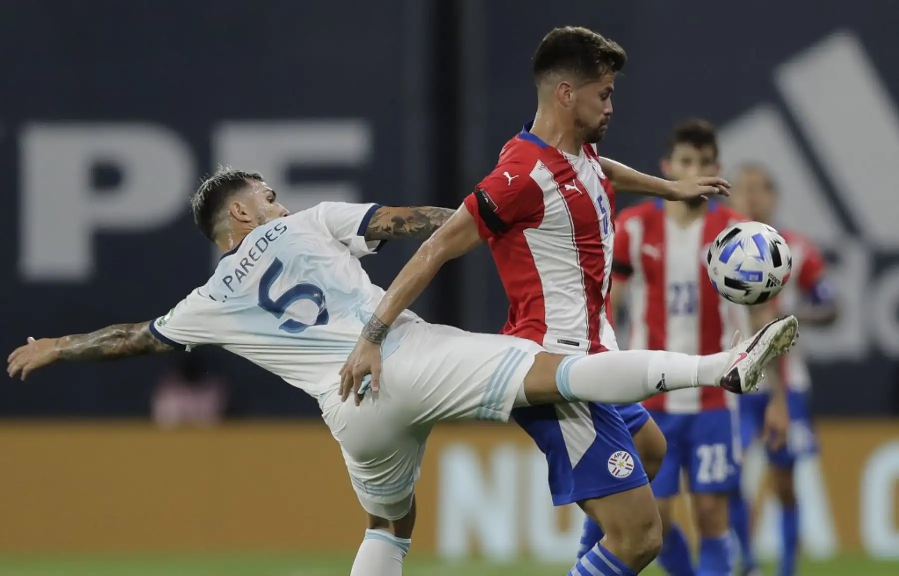 El argentino Leandro Paredes (izq.) y el paraguayo Gastón Giménez compiten por el balón durante su partido de fútbol a puerta cerrada clasificatorio sudamericano para la Copa Mundial de la FIFA 2022 en el Estadio La Bombonera en Buenos Aires. Foto: AFP