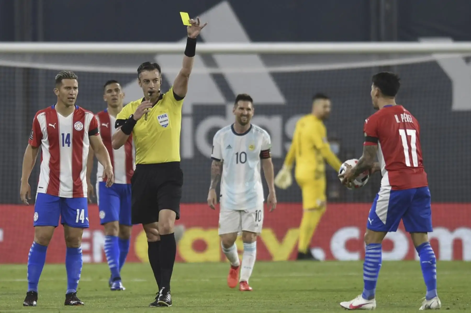 El árbitro brasileño Raphael Claus muestra una tarjeta amarilla al paraguayo Hernán Pérez durante el partido de fútbol a puerta cerrada clasificatorio sudamericano para la Copa Mundial de la FIFA 2022 entre Argentina y Paraguay en el Estadio La Bombonera en Buenos Aires. Foto: AFP