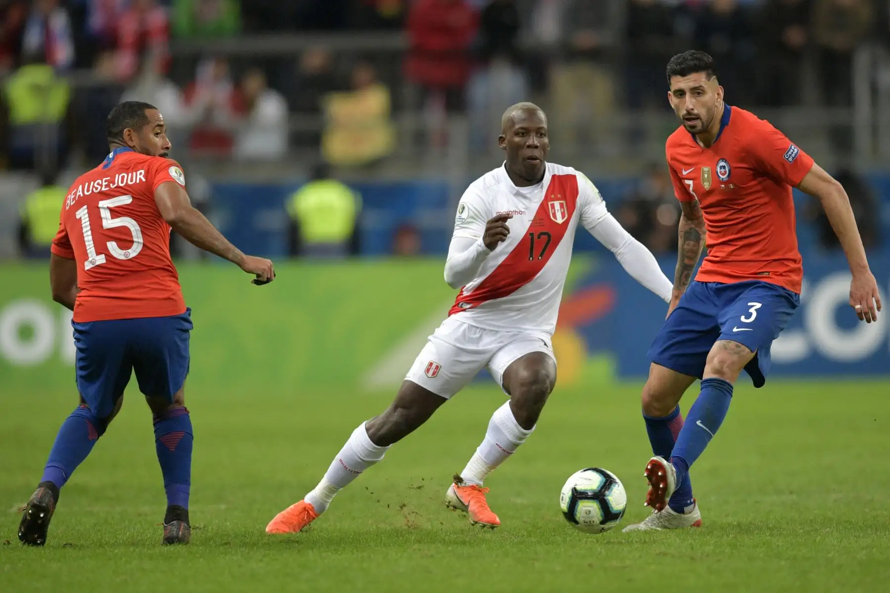 El peruano Luis Advincula  compite por el balón con los chilenos Guillermo Maripan  y Jean Beausejour durante el partido de semifinales del torneo de fútbol de la Copa América en 2019.
Foto: AFP