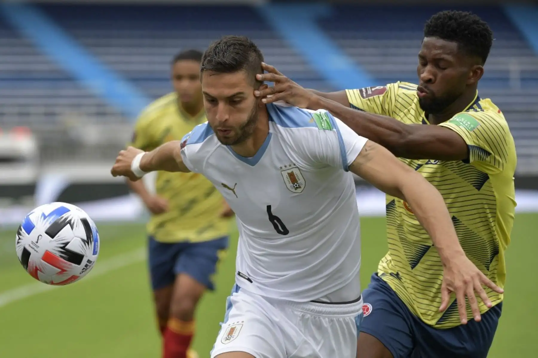 El uruguayo Rodrigo Bentancur (izq.) y el colombiano Jefferson Lerma compiten por el balón durante su partido de fútbol a puerta cerrada clasificatorio sudamericano para la Copa Mundial de la FIFA 2022 en el Estadio Metropolitano de Barranquilla, Colombia. Foto: AFP