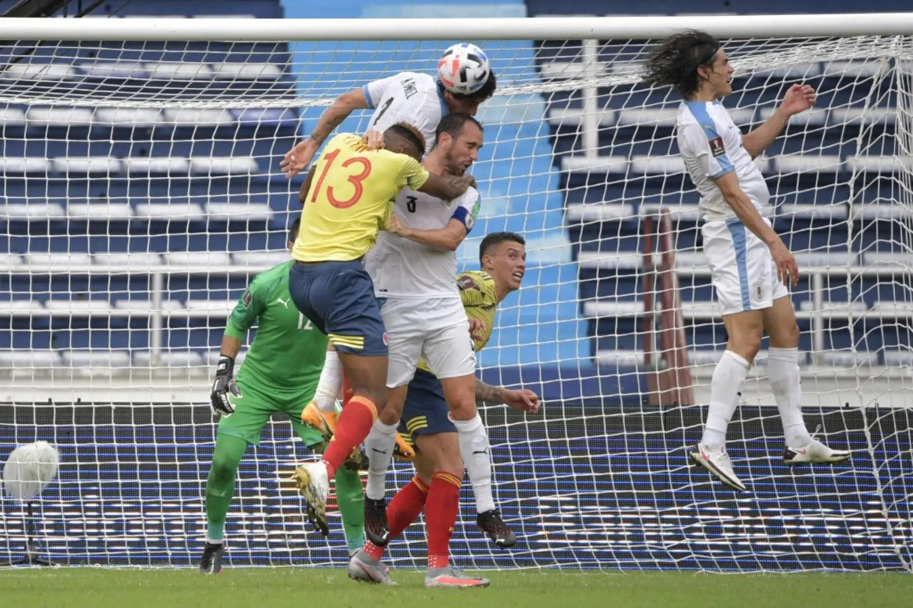 El colombiano Yerry Mina (izq.) Y el uruguayo José María Giménez (arriba) y Diego Godin saltan por el balón durante su partido de fútbol a puerta cerrada clasificatorio sudamericano para la Copa Mundial de la FIFA 2022 en el Estadio Metropolitano de Barranquilla, Colombia. Foto: AFP