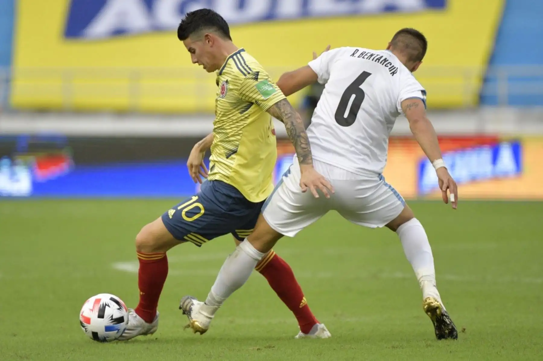 El colombiano James Rodríguez (izq.) es desafiado por el uruguayo Rodrigo Bentancur durante su partido de fútbol a puerta cerrada clasificatorio sudamericano para la Copa Mundial de la FIFA 2022 en el Estadio Metropolitano de Barranquilla, Colombia. Foto: AFP