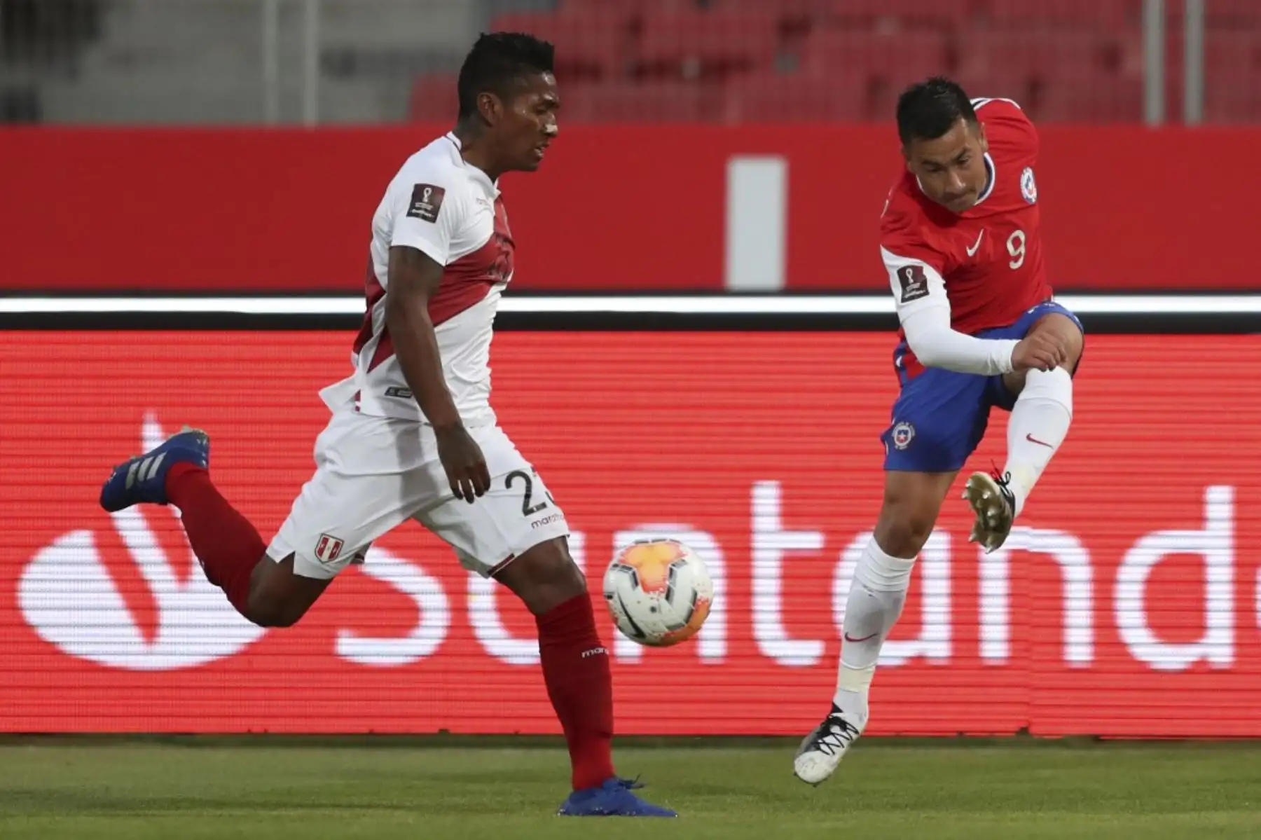 Foto: ANDINA/Jhonel Rodríguez El chileno Jean Meneses (derecha) golpea el balón junto al peruano Pedro Aquino durante su partido de fútbol a puerta cerrada clasificatorio sudamericano para la Copa Mundial de la FIFA 2022 en el Estadio Nacional de Santiago. Foto: AFP