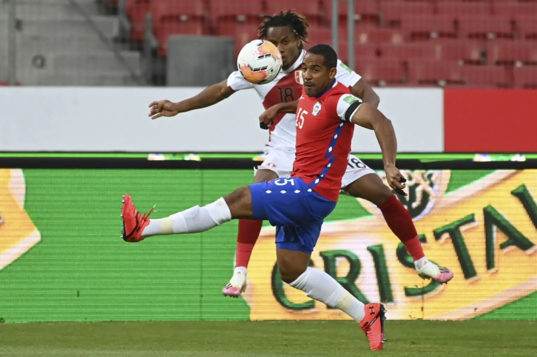 El peruano Andre Carrillo (atrás) y el chileno Jean Beausejour compiten por el balón durante su partido de fútbol clasificatorio sudamericano a puerta cerrada para la Copa Mundial de la FIFA 2022 en el Estadio Nacional de Santiago. Foto: AFP
