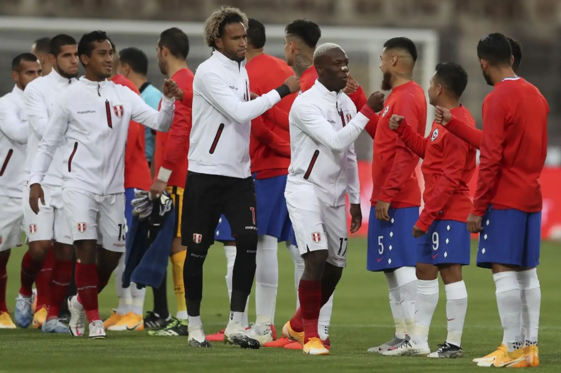 Jugadores de Perú (de blanco) y Chile se saludan antes del inicio de su partido clasificatorio Sudamericano a la Copa Mundial de la FIFA 2022 a puertas cerradas en el Estadio Nacional de Santiago. Foto: AFP
