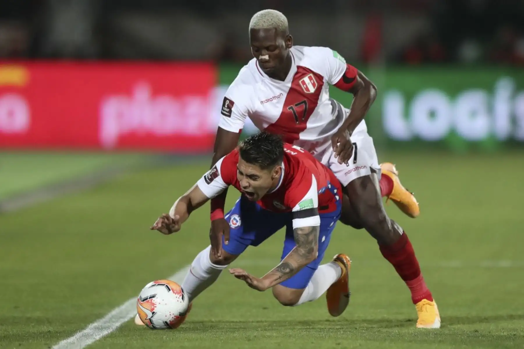 El chileno Felipe Mora cae mientras compite por el balón con el peruano Luis Advincula durante su partido de fútbol a puertas cerradas clasificatorio sudamericano para la Copa Mundial de la FIFA 2022 en el Estadio Nacional de Santiago. Foto: AFP