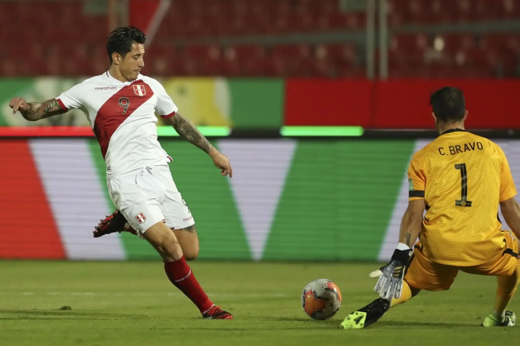 El peruano Gianluca Lapadula (izq.) intenta superar al arquero chileno Claudio Bravo durante su partido de fútbol a puerta cerrada clasificatorio sudamericano para la Copa Mundial de la FIFA 2022 en el Estadio Nacional de Santiago. Foto: AFP