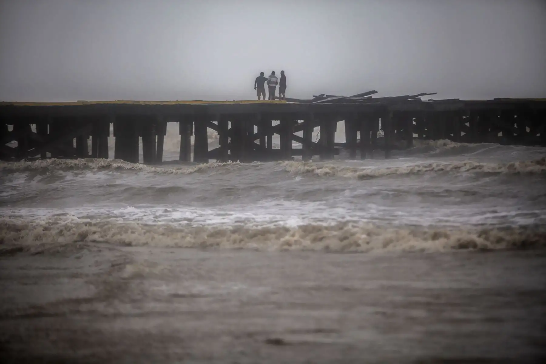 Algunas personas caminan por el muelle de Puerto Cabezas que fue destruido después del paso del huracán Iota, en Bilwi, Nicaragua. Foto: AFP