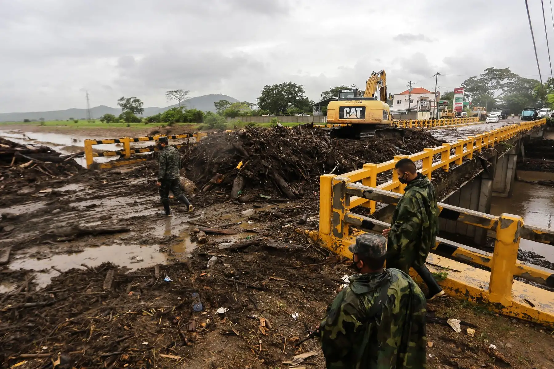 Una retroexcavadora realiza trabajos de limpieza tras el paso de la tormenta tropical mientras los miembros de las Fuerzas Armadas supervisan las acciones en el municipio de La Lima, departamento de Cortés, norte de Honduras. Foto: AFP
