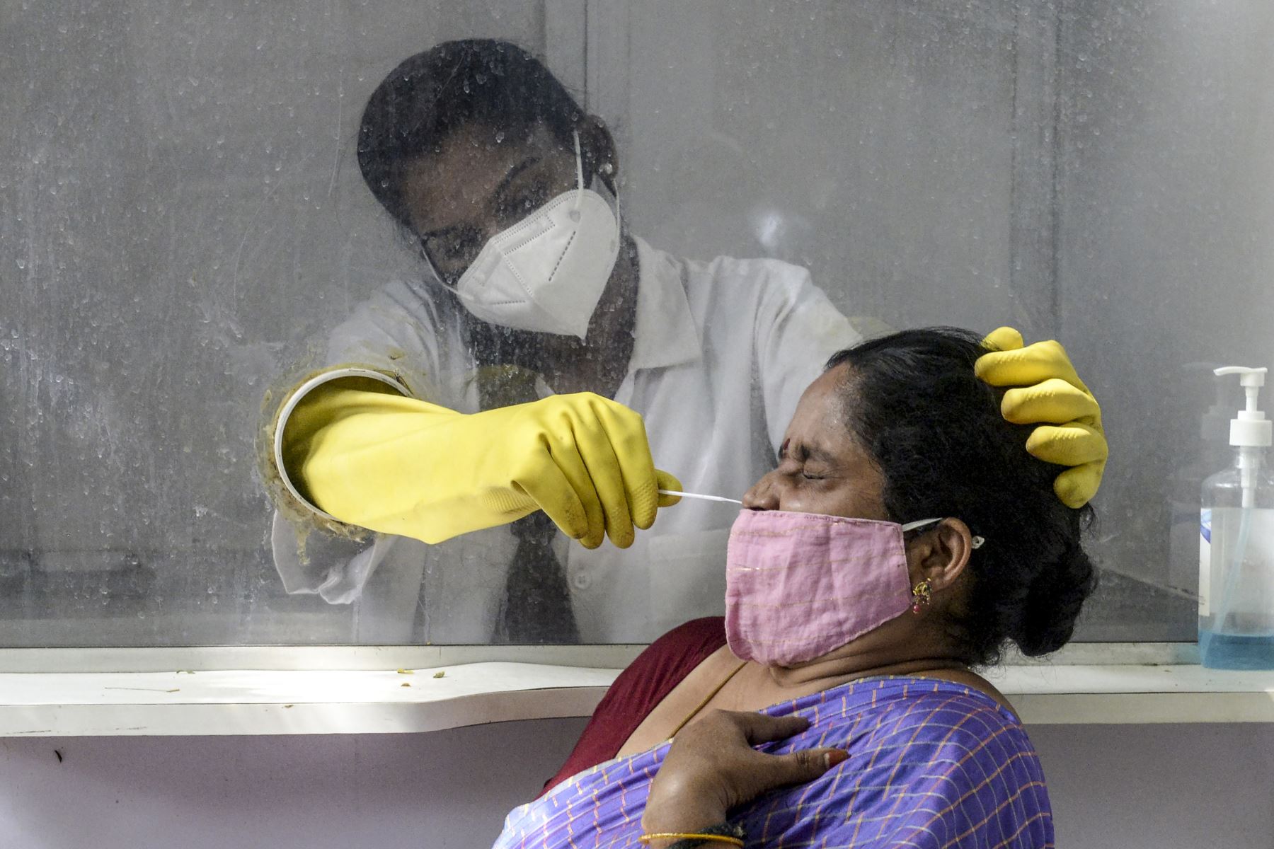 Un trabajador de salud  recolecta una muestra de hisopo de una mujer a la que se le hizo la prueba del coronavirus covid-19 en un centro de salud primario en Hyderabad, cuando el número de casos de coronavirus en India superó los nueve millones.
Foto: AFP