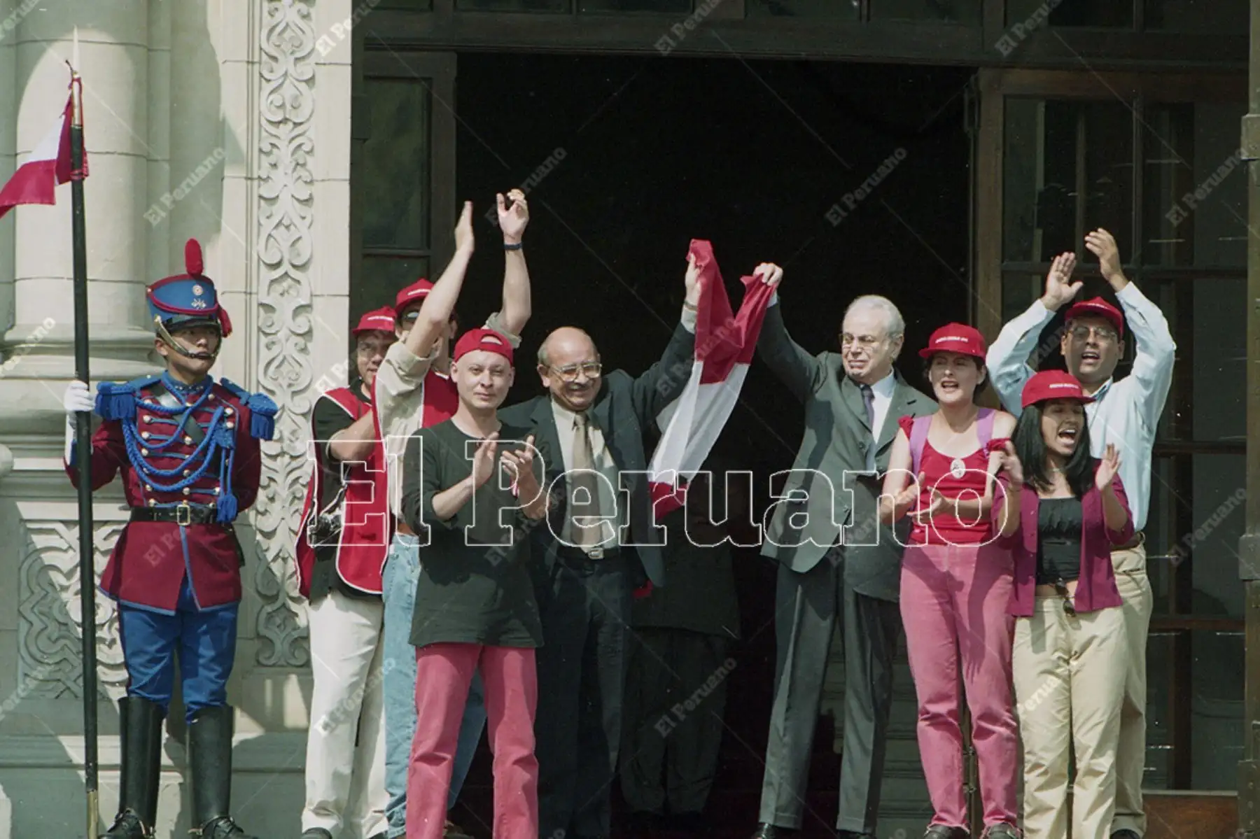 Lima - 24 noviembre 2000. El presidente Valentín Paniagua, junto al designado premier Javier Pérez de Cuéllar, flamea la bandera peruana que le entregó el Colectivo Sociedad Civil. El gesto del mandatario generó aplausos de cientos de ciudadanos que se congregaron en la Plaza de Armas de Lima.  Foto: Diario Oficial El Peruano / Víctor Palomino