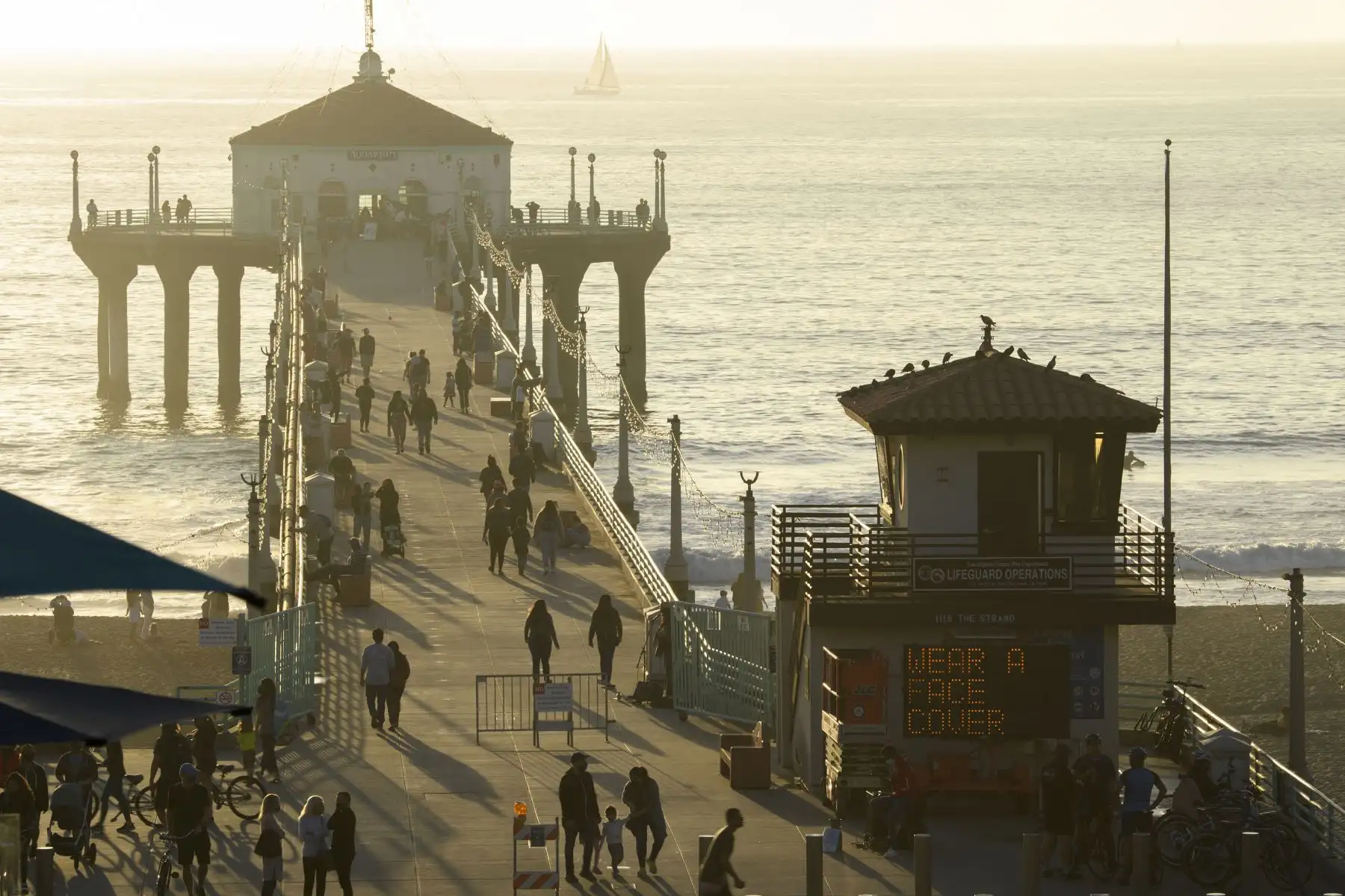 La gente camina en el muelle en Manhattan Beach, California, unas horas antes del inicio del nuevo toque de queda. Foto: AFP