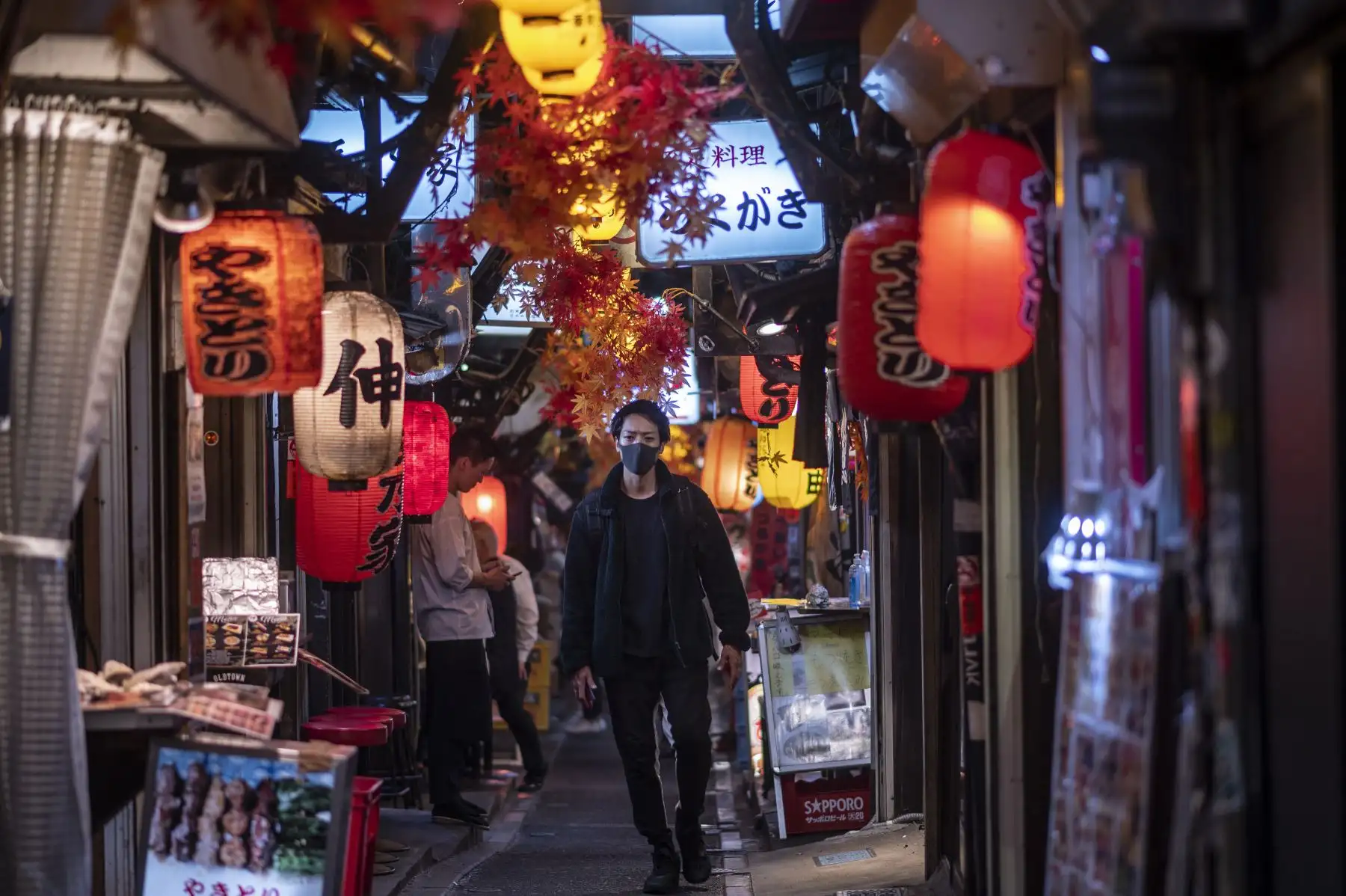 Un hombre que llevaba una mascarilla como medida preventiva ante el coronavirus camina por el área de restaurantes del callejón Omoide Yokocho en el distrito Shinjuku de Tokio. Foto: AFP
