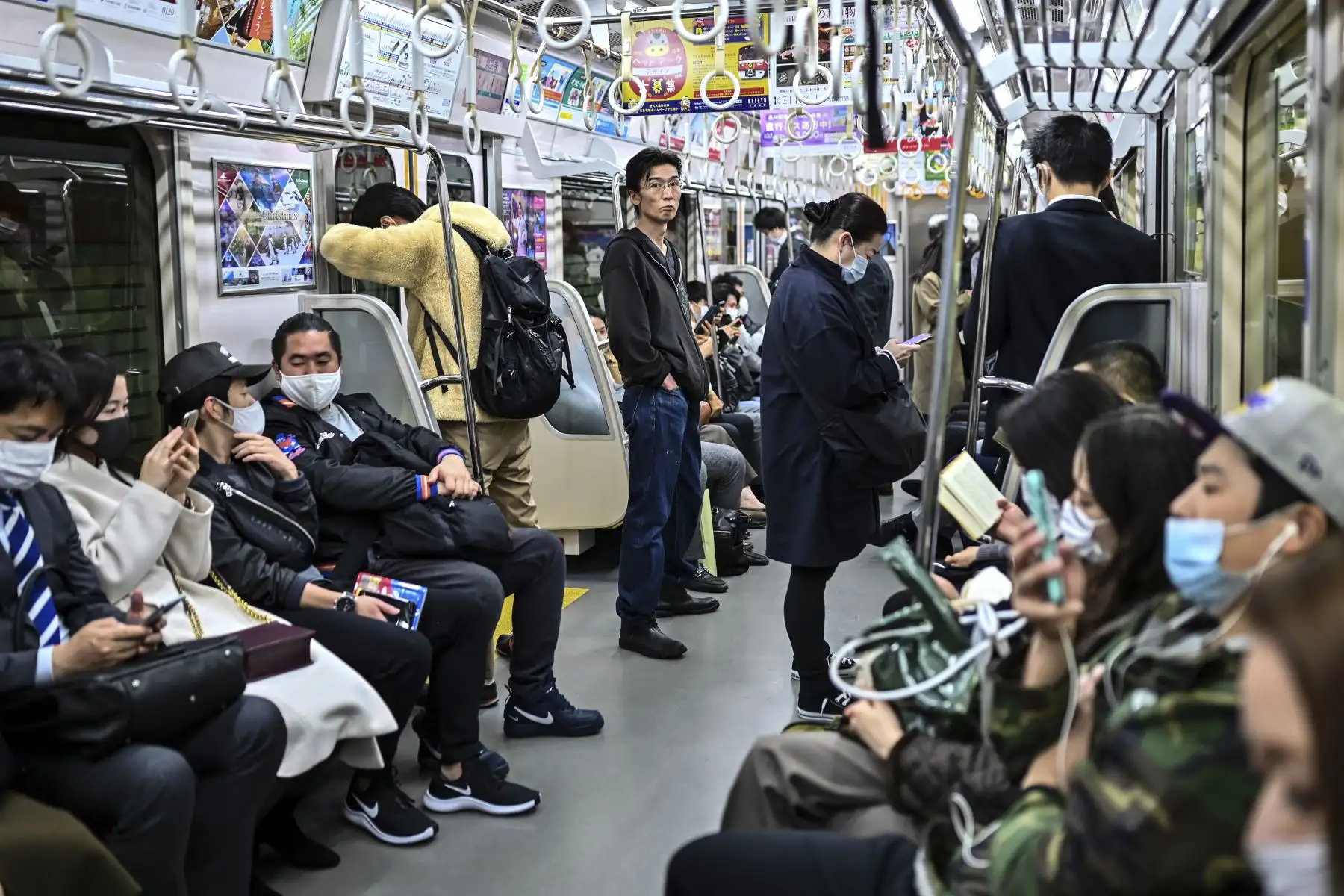 Las personas que usan mascarillas como medida preventiva ante el coronavirus, viajan a última hora de la noche en Tokio. Foto: AFP