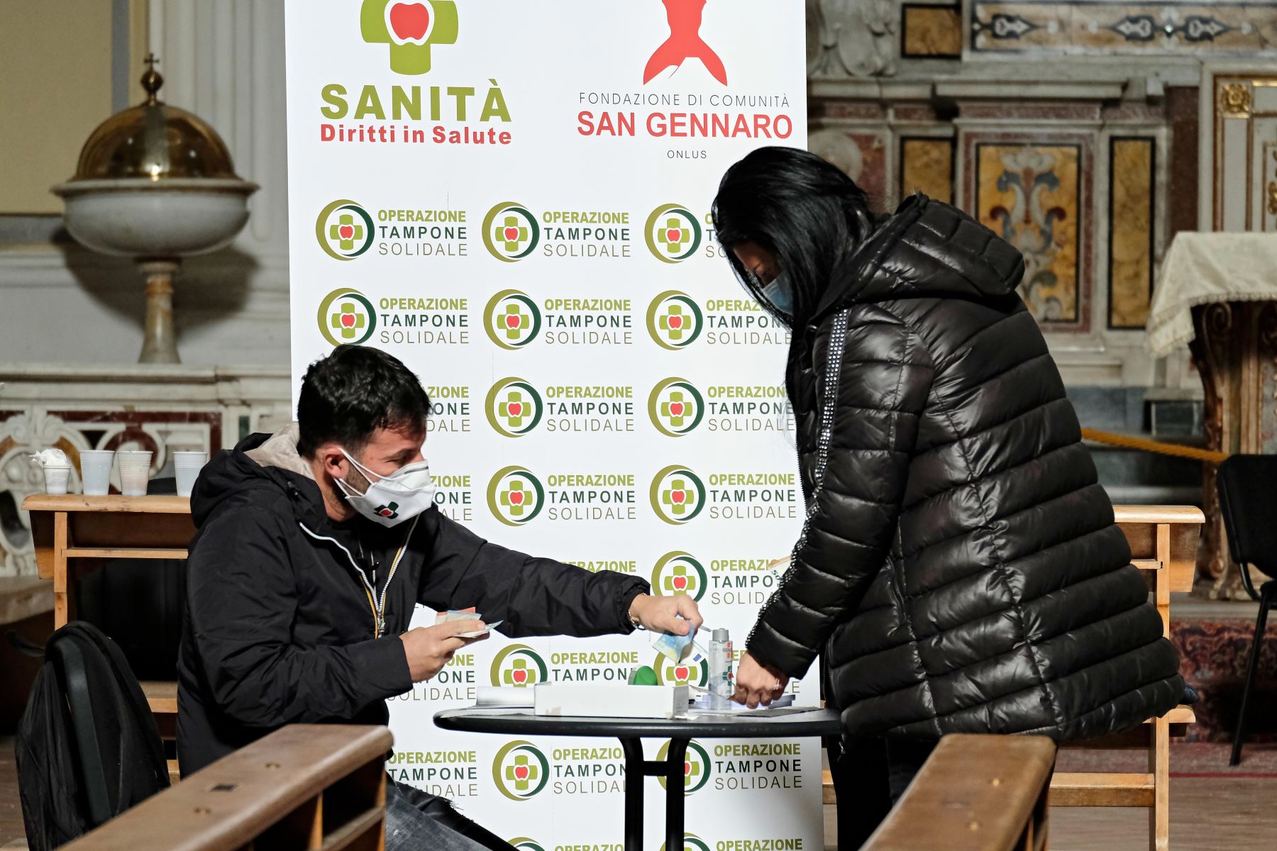 Un residente local dona dinero durante una campaña de prueba rápida de antígenos para la enfermedad Covid-19 causada por el nuevo coronavirus, en la Basílica de San Severo  en el distrito de Rione Sanita en el centro de Nápoles.
Foto: AFP