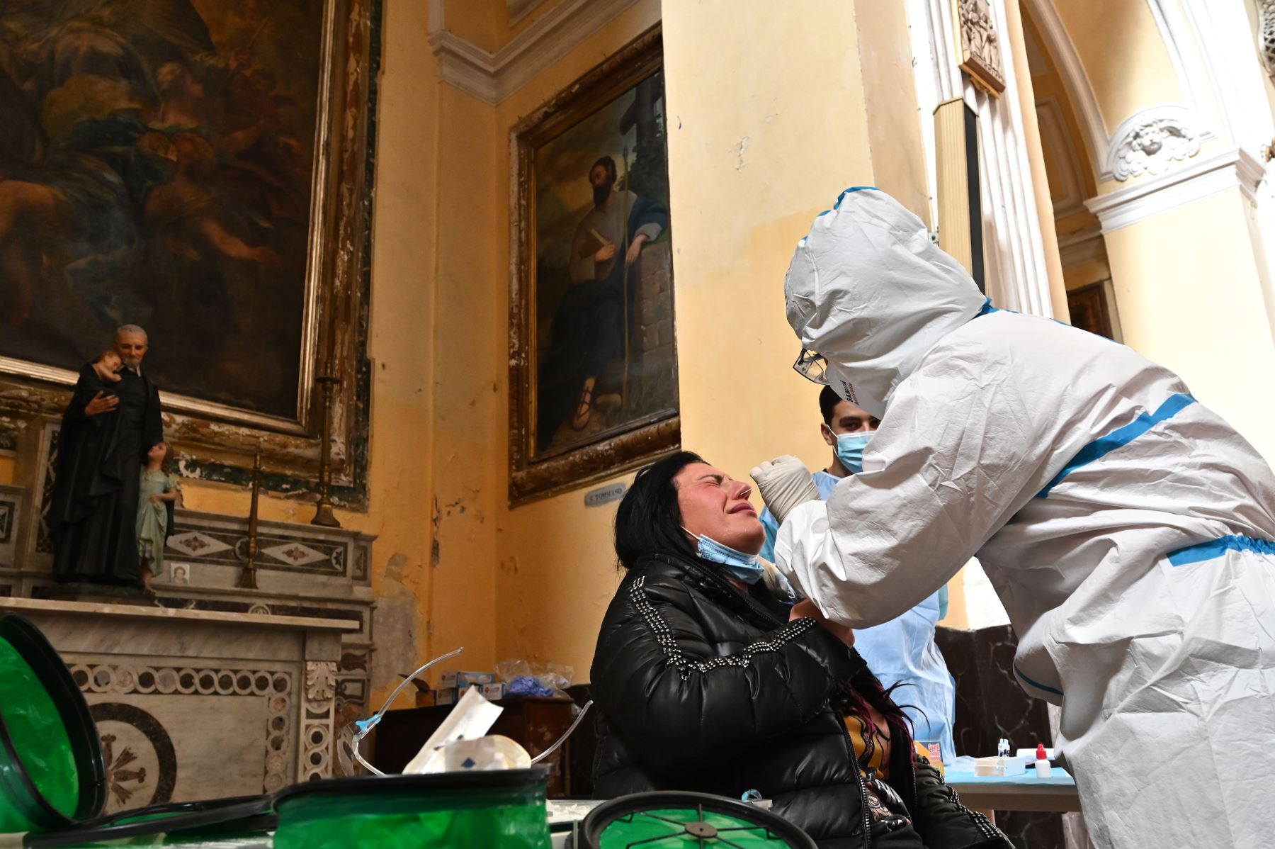 Un trabajador de la salud con equipo de protección personal  toma una muestra de hisopo de una mujer durante una campaña de prueba rápida de antígenos para la enfermedad Covid-19 causada por el nuevo coronavirus, en la Basílica de San Severo en el centro de Nápoles.
Foto: AFP