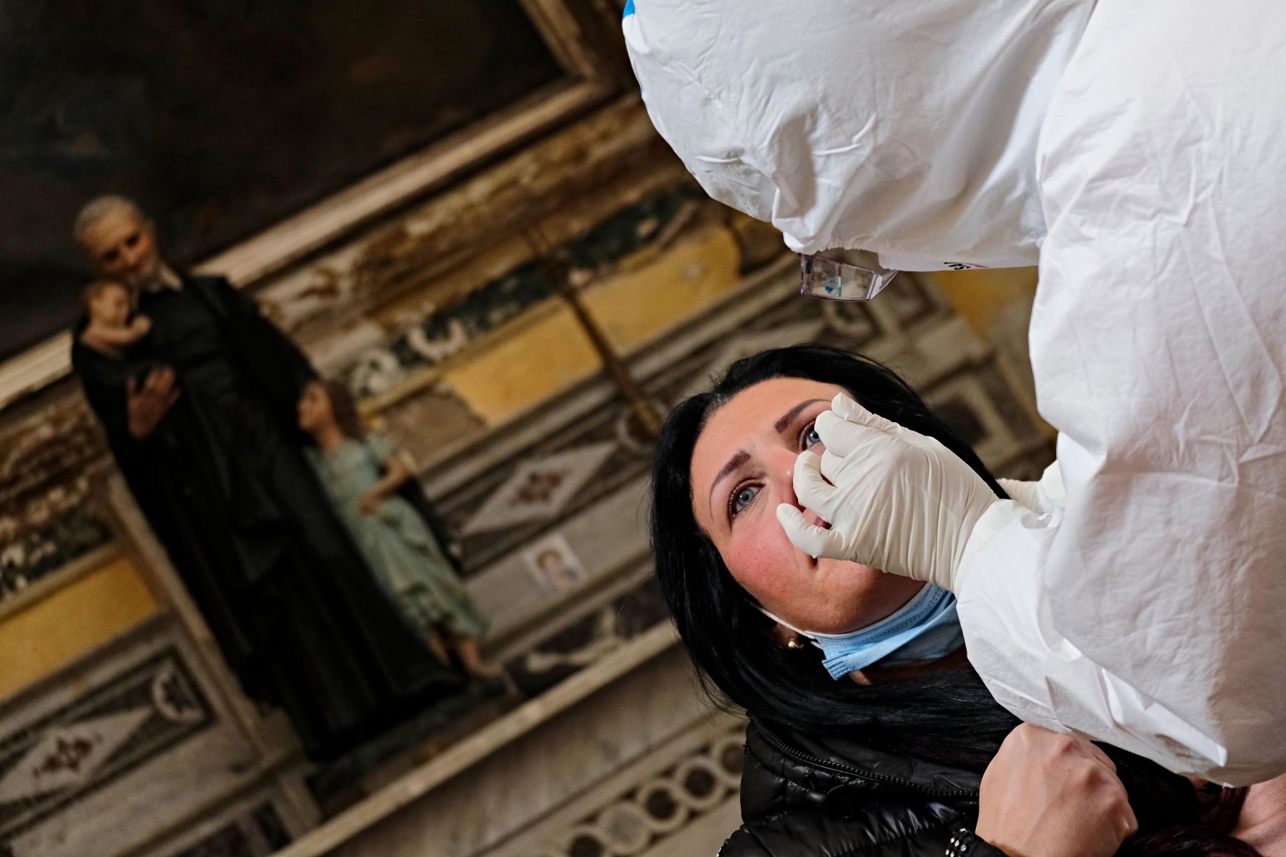 Un trabajador de la salud con equipo de protección personal  toma una muestra de hisopo de una mujer durante una campaña de prueba rápida de antígenos para la enfermedad Covid-19 causada por el nuevo coronavirus, en la Basílica de San Severo  en el centro de Nápoles.
Foto: AFP