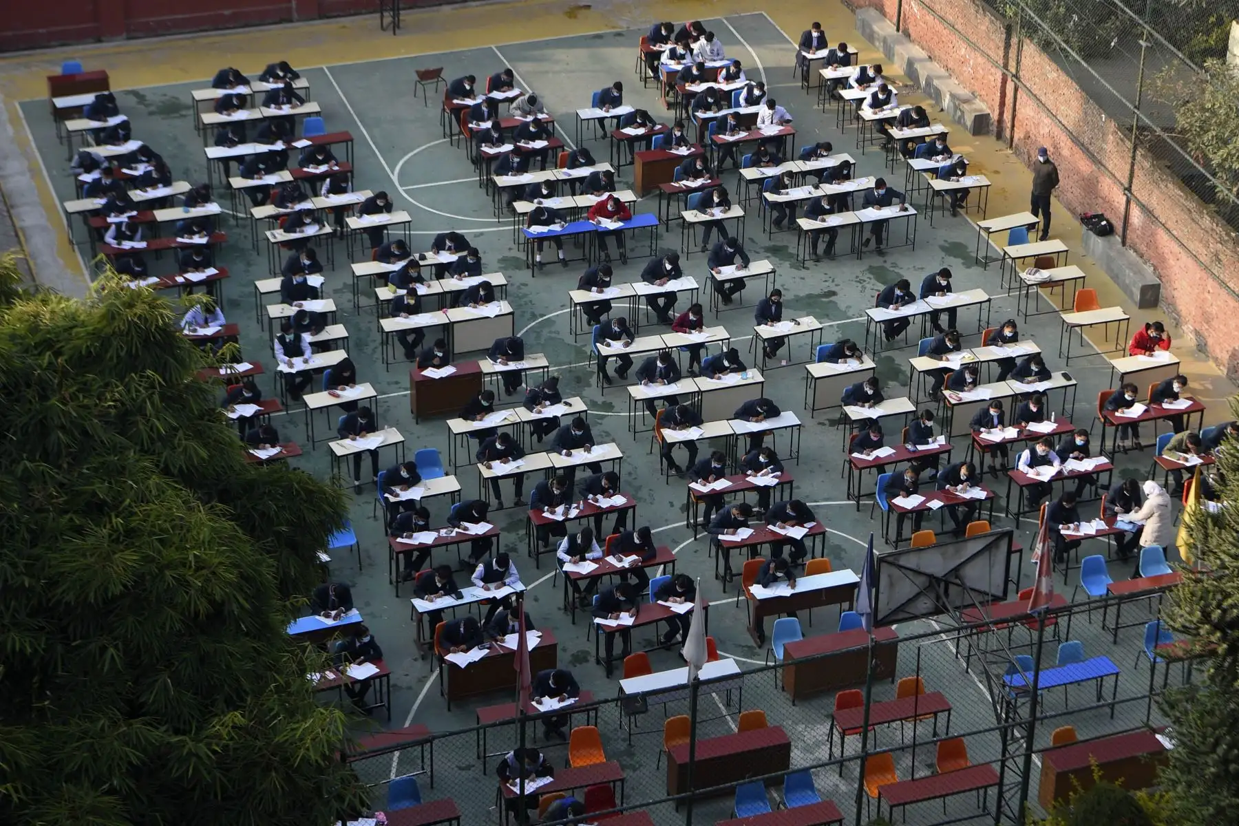 Estudiantes que usan mascarillas rinden el examen en el patio de la escuela en medio de la pandemia del coronavirus Covid-19 en Katmandú. Foto: AFP