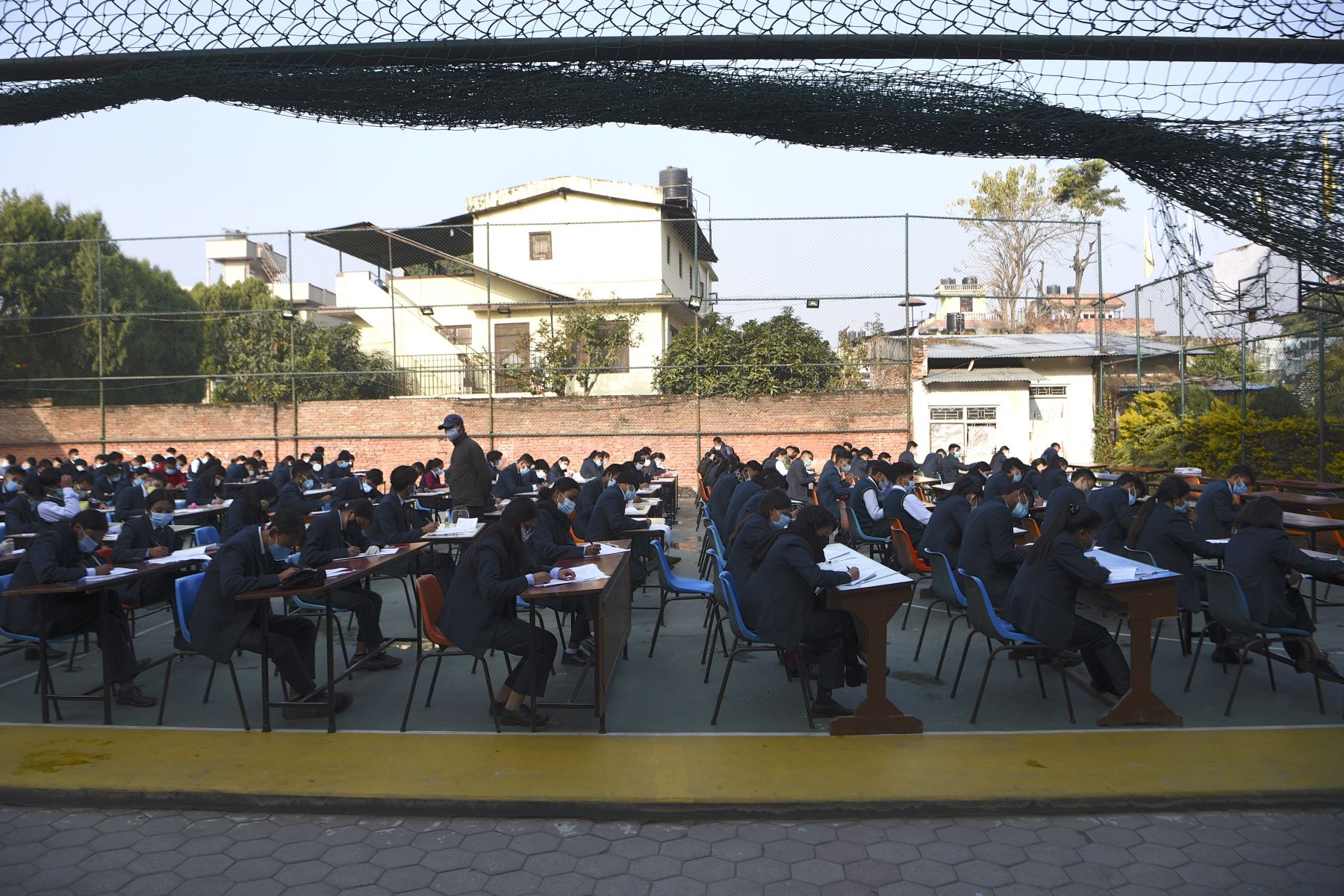 Estudiantes que usan mascarillas rinden el examen en el patio de la escuela en medio de la pandemia del Covid-19 en Katmandú. Foto: AFP