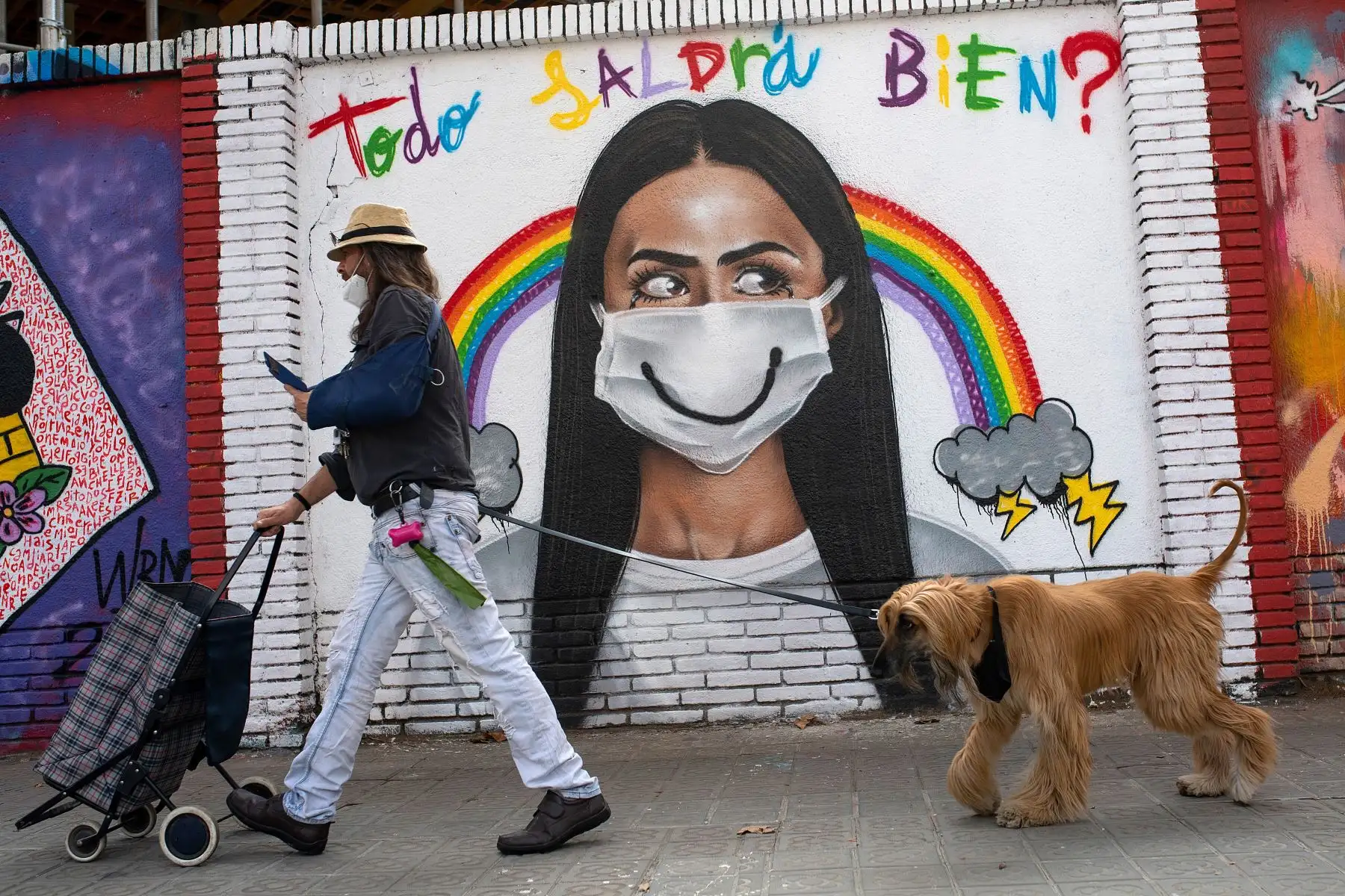 Un ciudadano que pasea a su mascota pasa junto a un mural en el centro de Barcelona. Foto: AFP